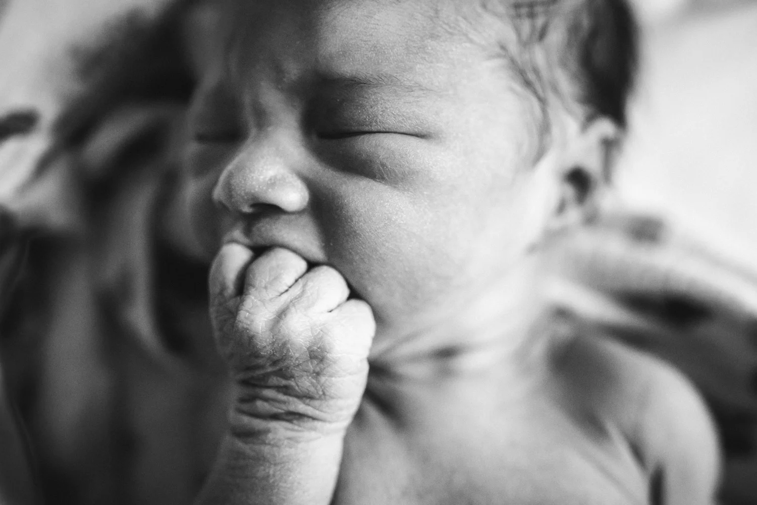 newborn chewing on his hand