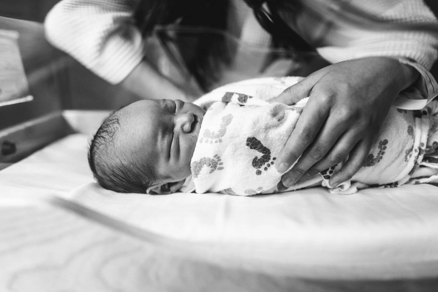 newborn in bassinet with mom's hand
