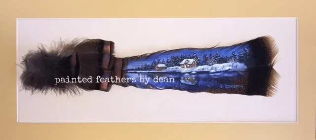  his is an acrylic painting of snow covered cabin nestled alongside a quite little lake, painted on one wild Eastern Turkey tail feather. The base of the feather's shaft is adorned with body and covert feathers. The feathers are matted and framed in 