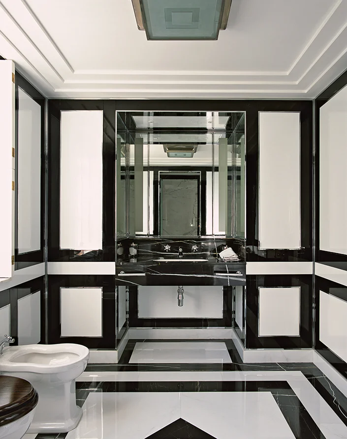 This bathroom is a study in black-and-white glass and marble; the design was devised to deceive the eye into believing the space is much larger than it is. 