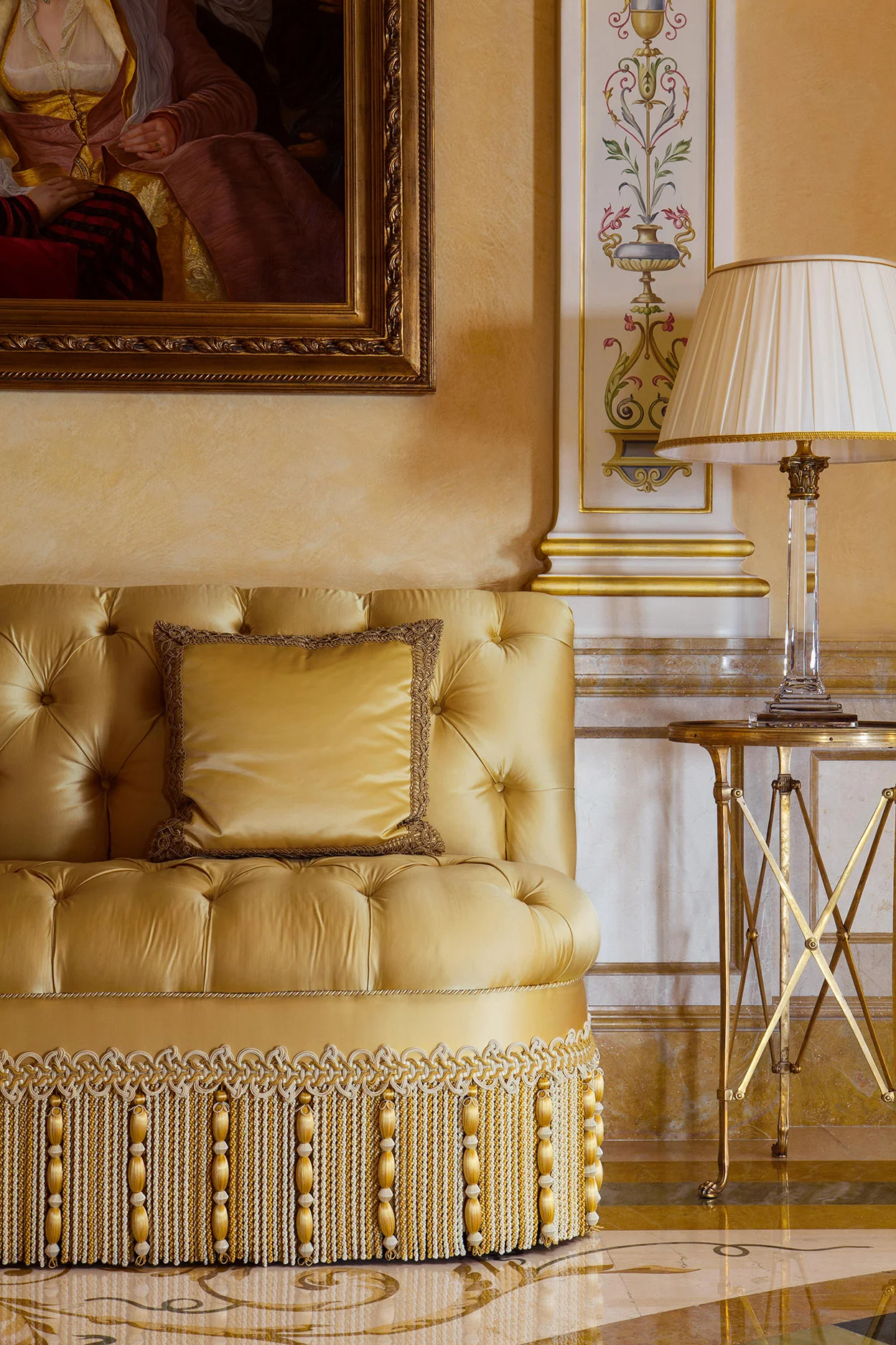 An intricately detailed silk-fringed sofa is one of the few pieces of furniture in the hall.
