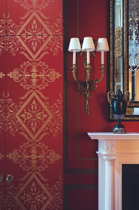 Woven Empire-style gold and red fabric has been used to conceal the closets on either side of the fireplace in this London dressing room - the remaining walls were then covered in the same red fabric, but without the pattern.