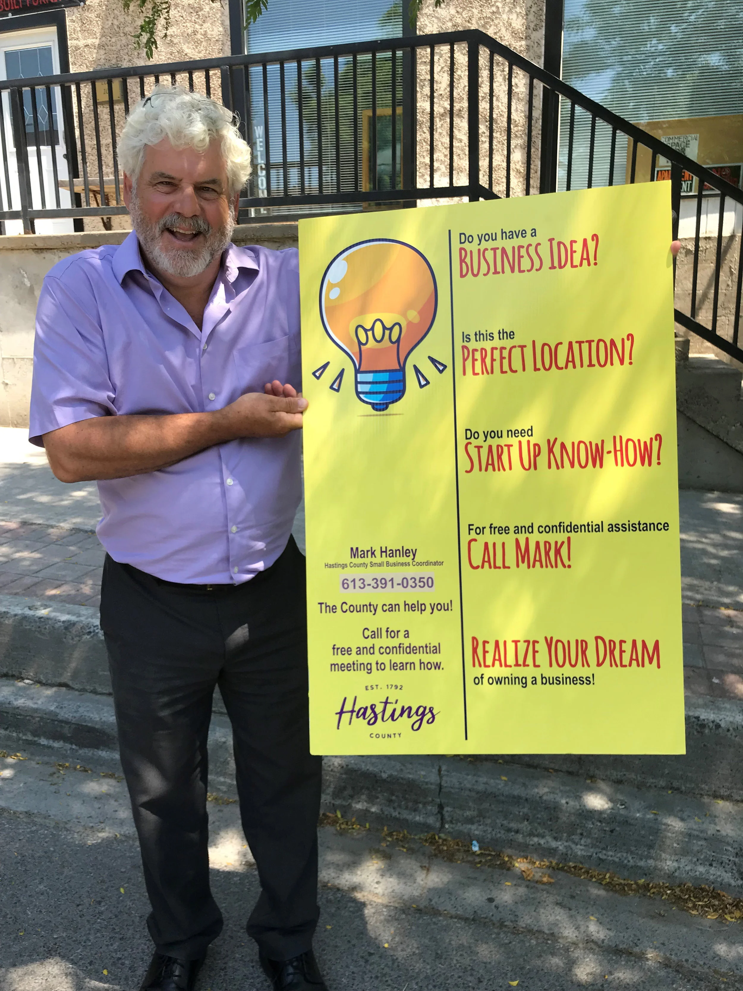 Mark Hanley, Small Business Coordinator, holds a Hastings County vacant business window sign.