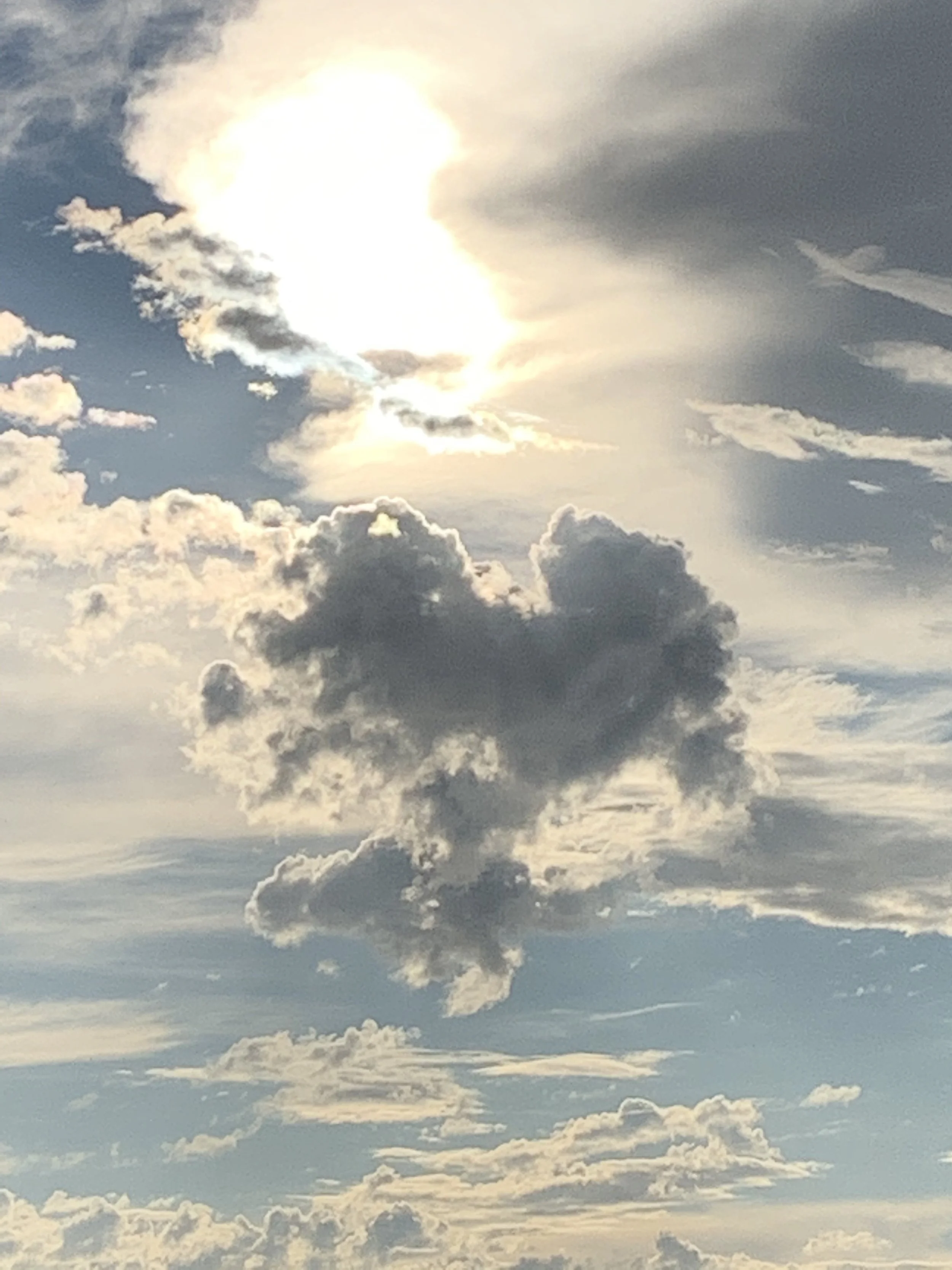 Sky with scattered clouds and sunlight shining through.
