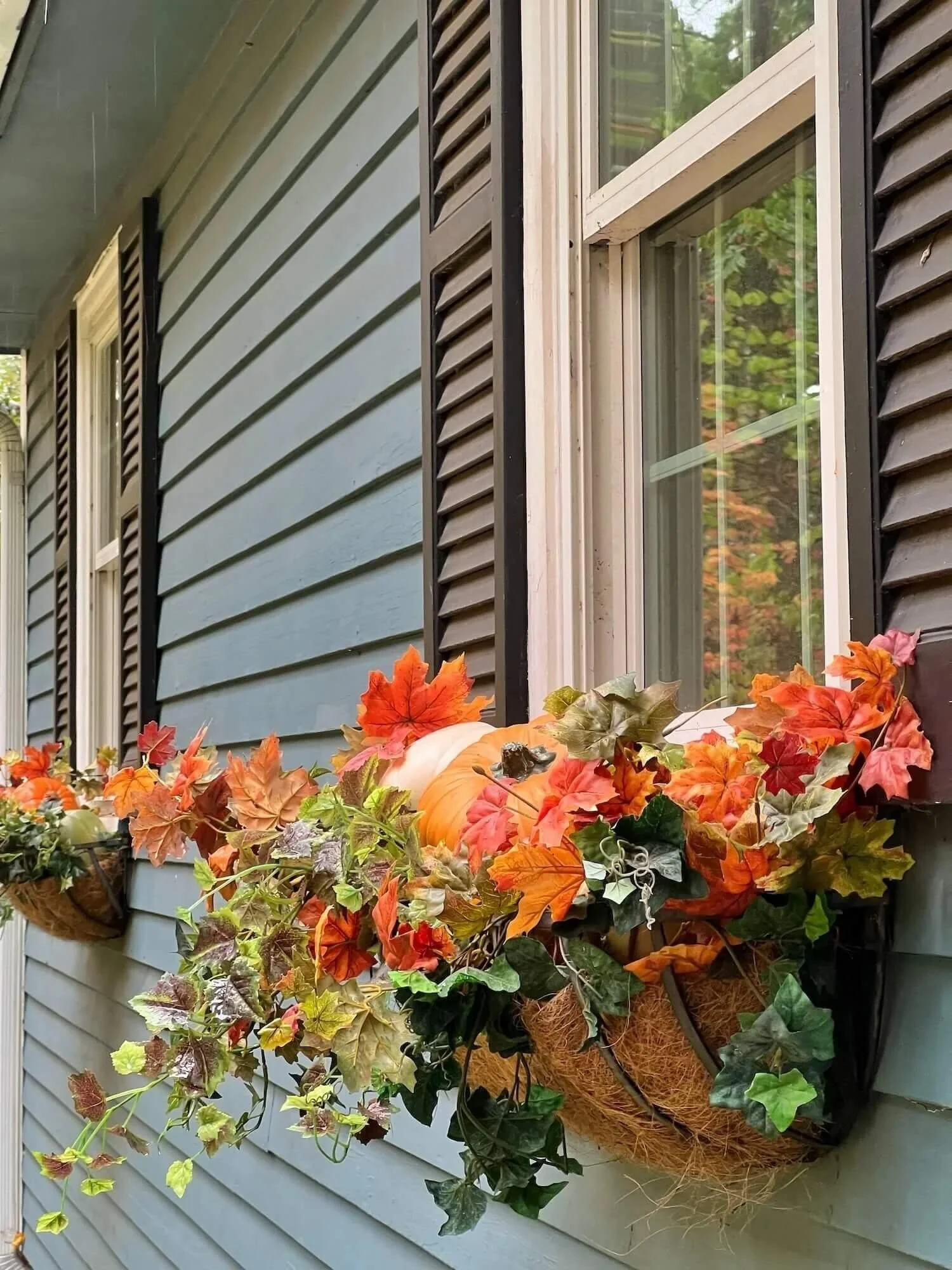 fall window boxes with pumpkins and faux autumn leaf branches
