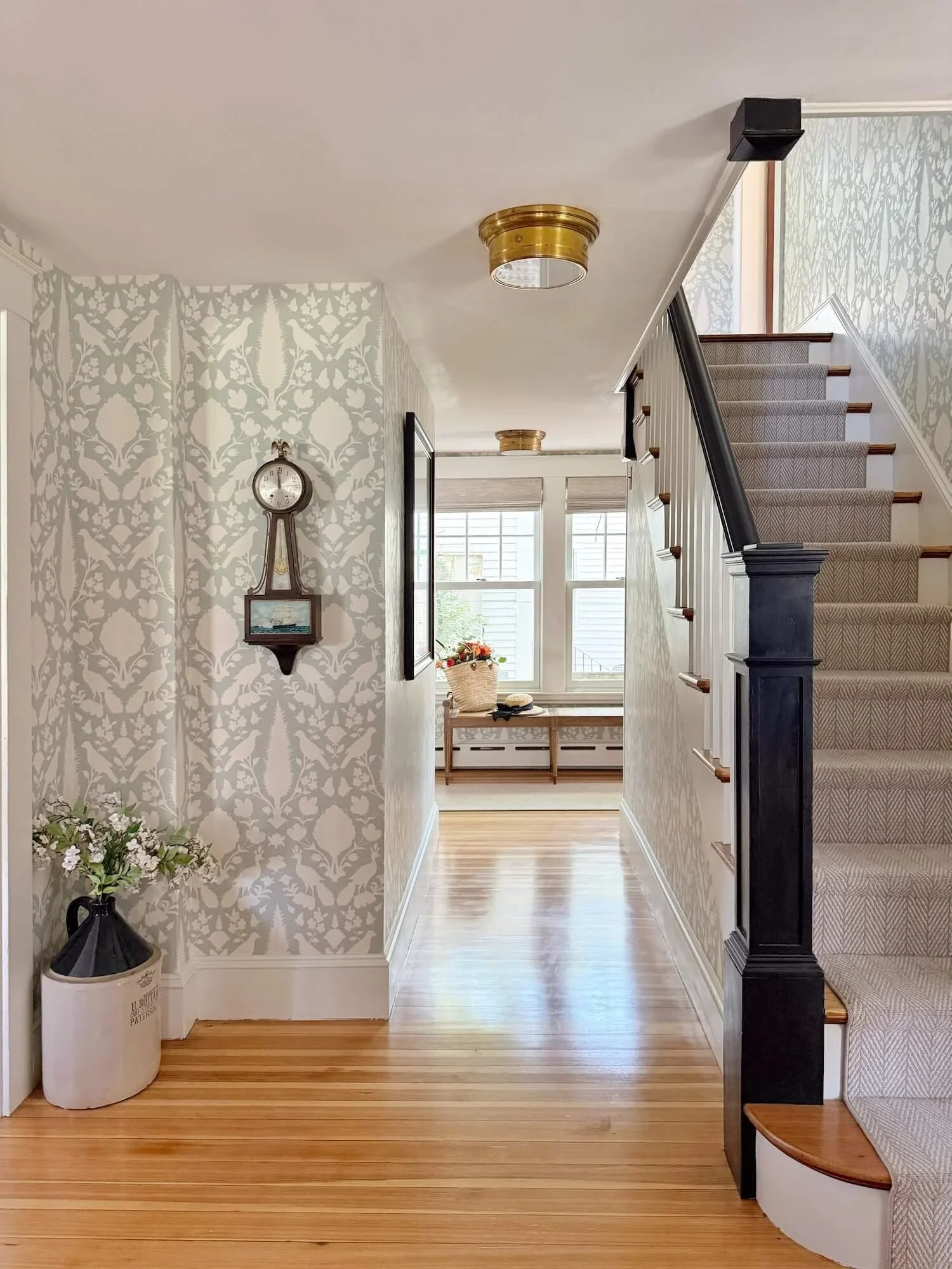 entry with wallpaper and black painted banister and newel post