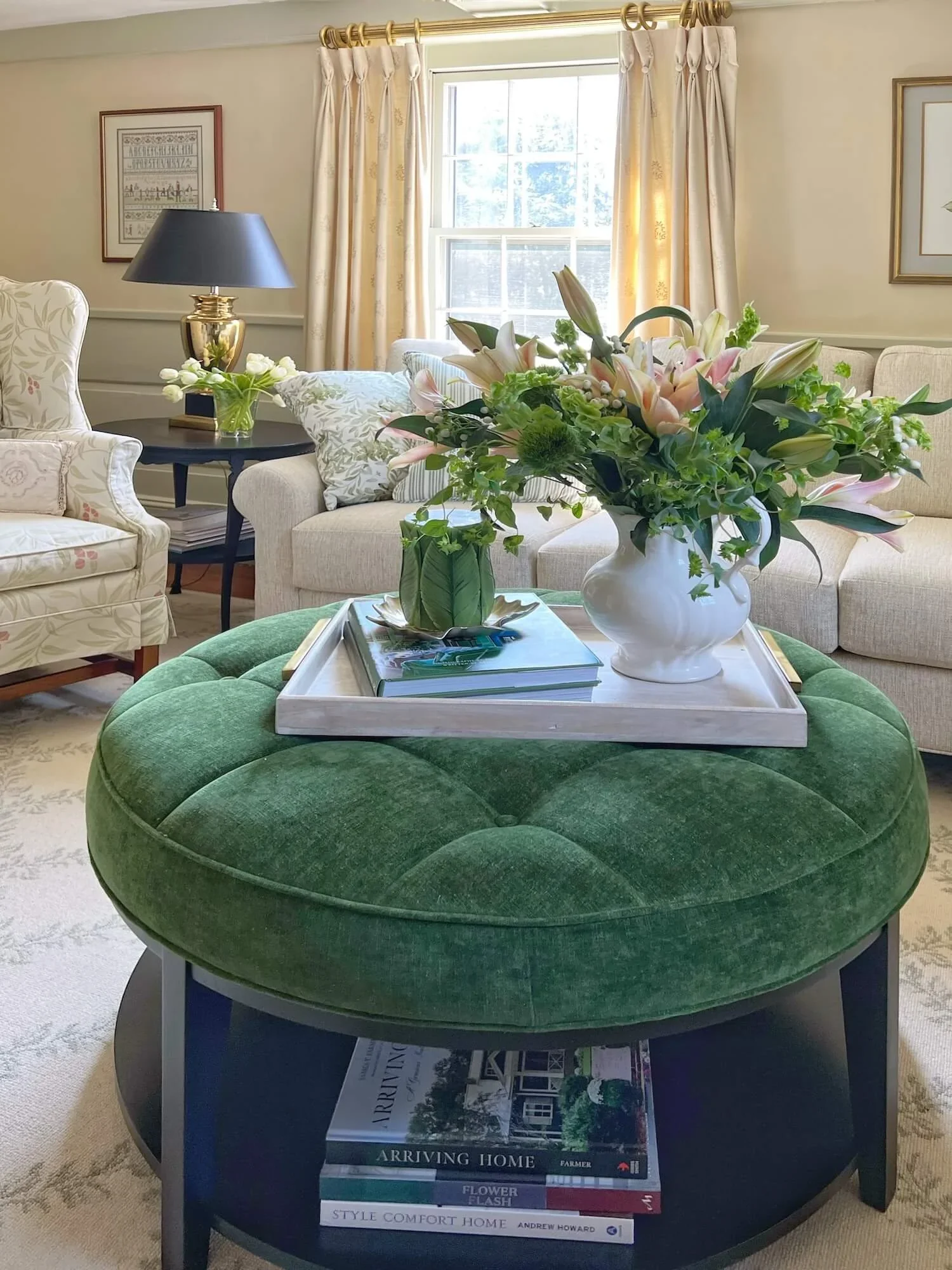 green table ottoman, black painted end table, neutral sectional, and slipcovered wing chairs