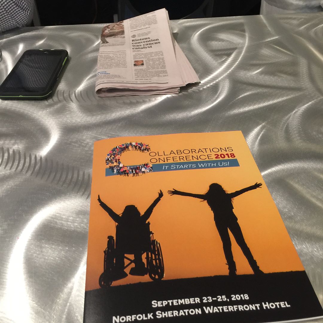 PHOTO: Program from attending.The 2018 Collaborations Conference. The program depicts two silhouettes of people. One person with a disability in a wheelchair and one able-bodied person holding their arms up in victory.