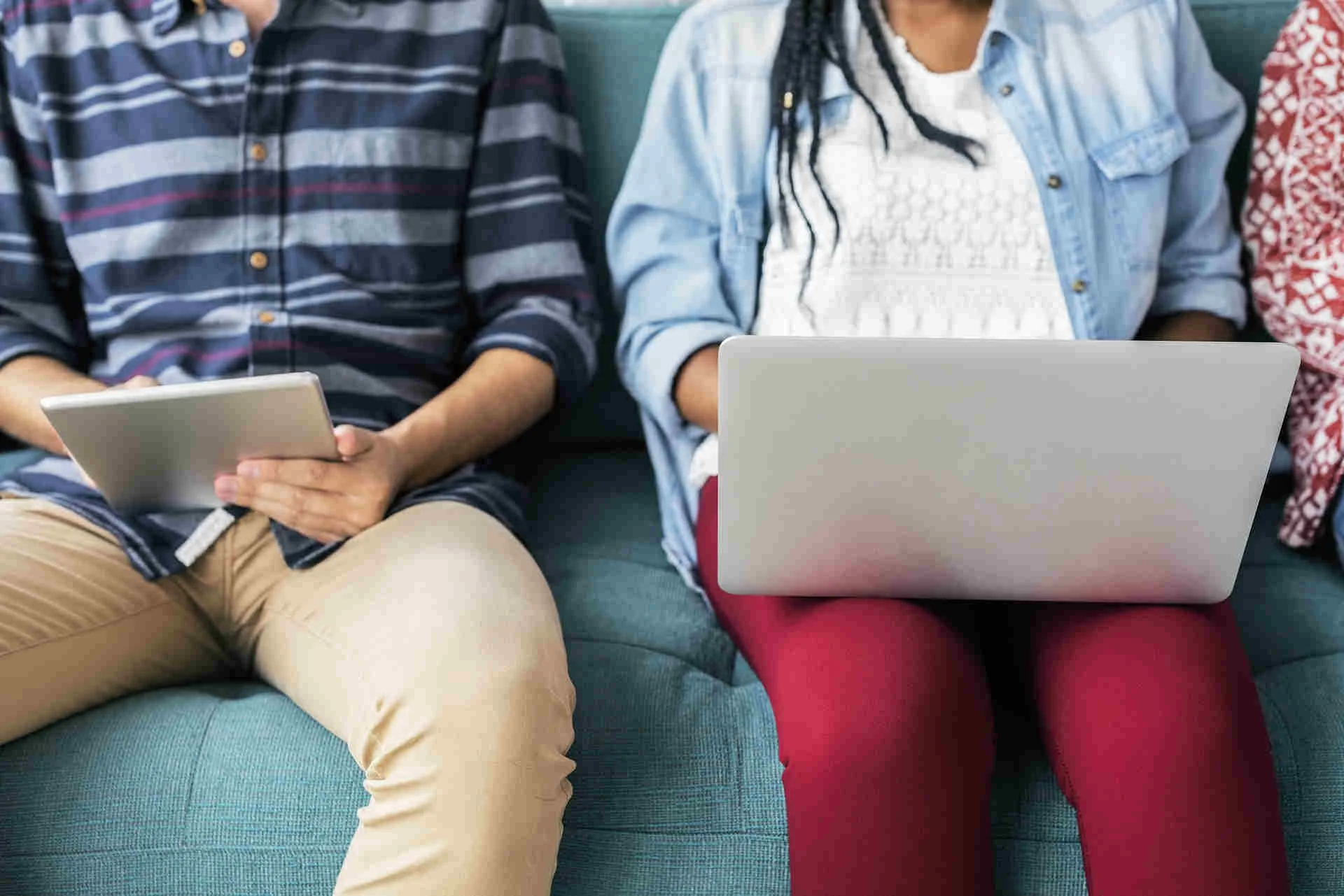 man using tablet and woman using laptop sitting on couch.jpg