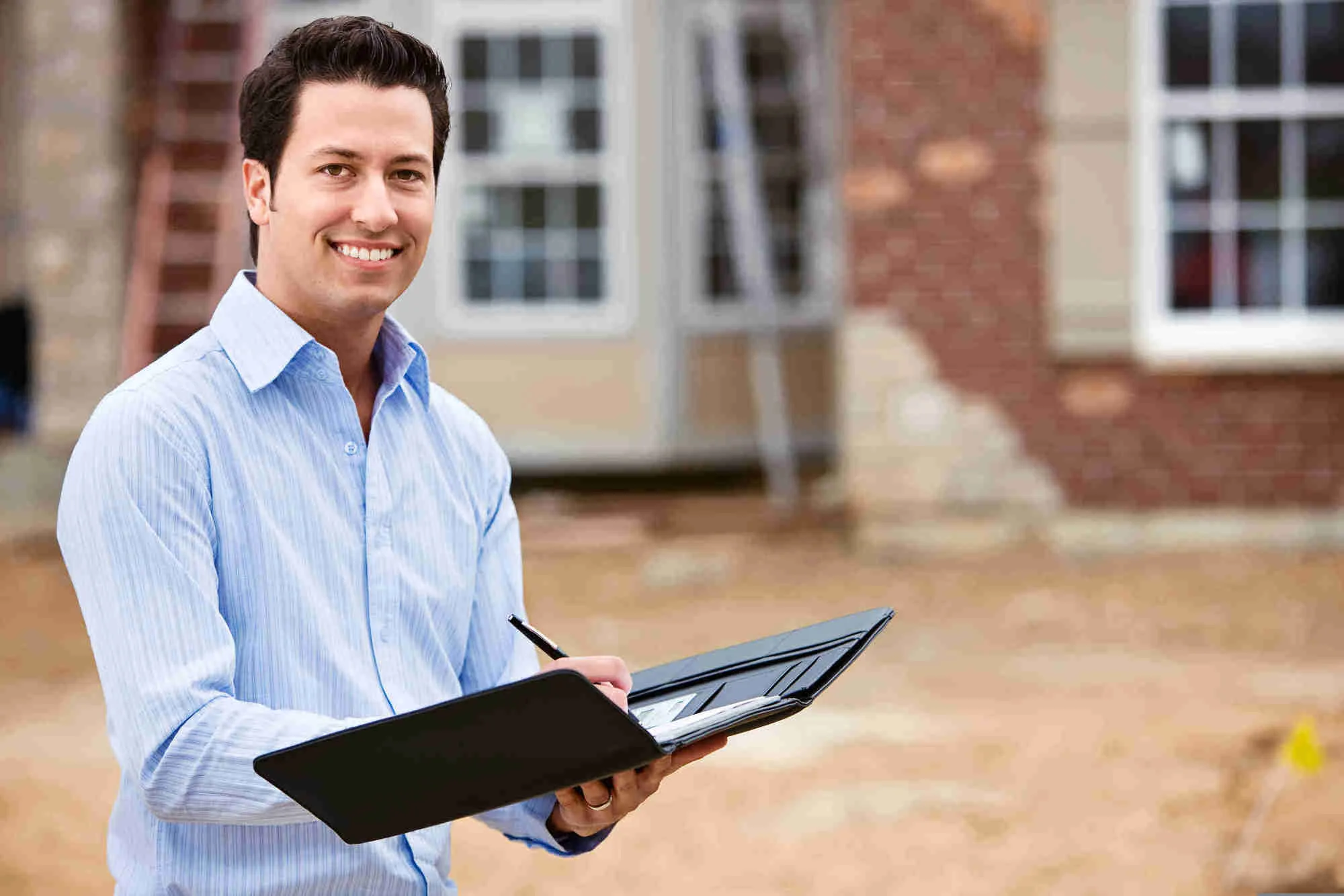 man writing notes with house in background.jpg