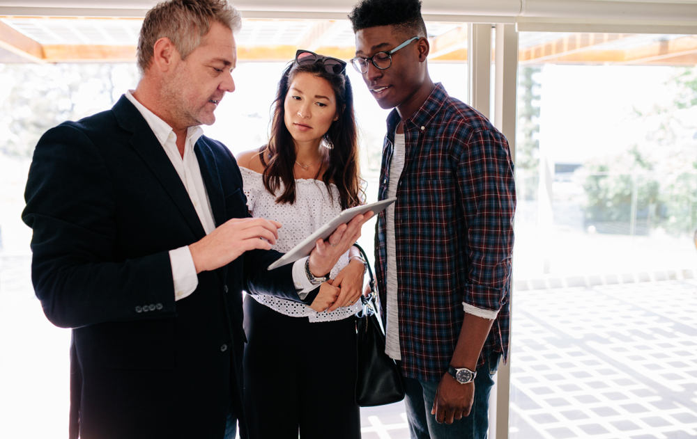 agent showing something on tablet to young mixed couple.jpg