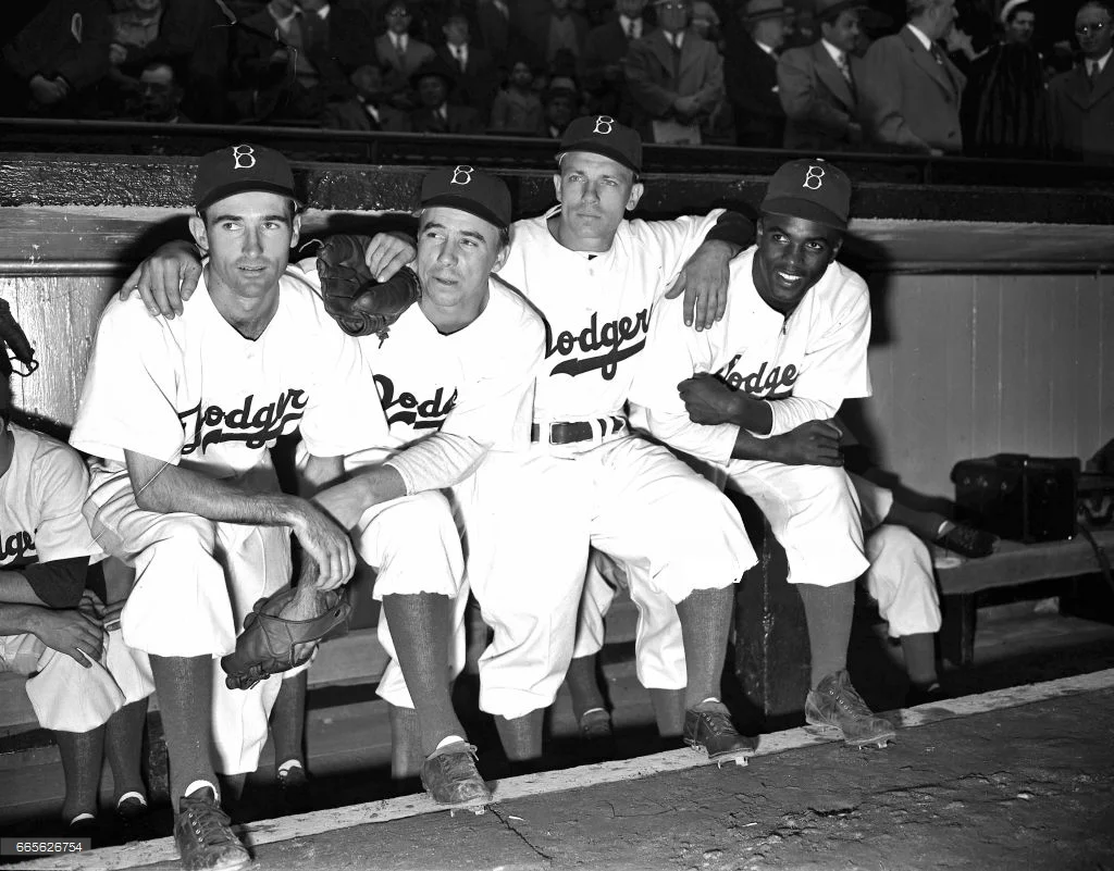 Dodger teammates pose with Jackie prior to the April 15, 1947 contest. L-R: Spider Jorgensen, Pee Wee Reese, Eddie Stanky, Robinson
