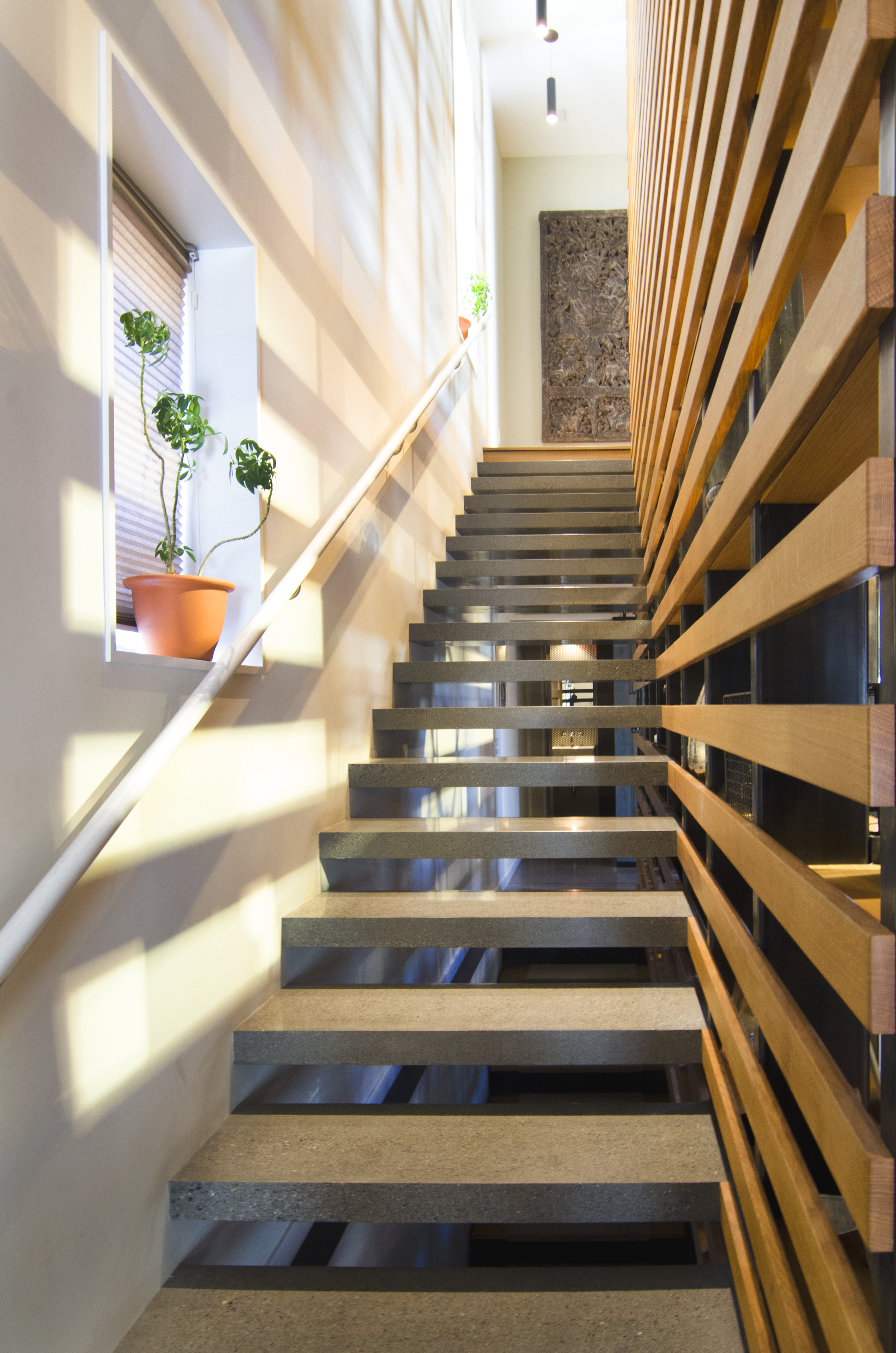Floating Concrete Stair/bookcase: Custom cast and polished concrete stair treads patterned into the spacing of the vertical steel tubing and the horizontal white oak railing.