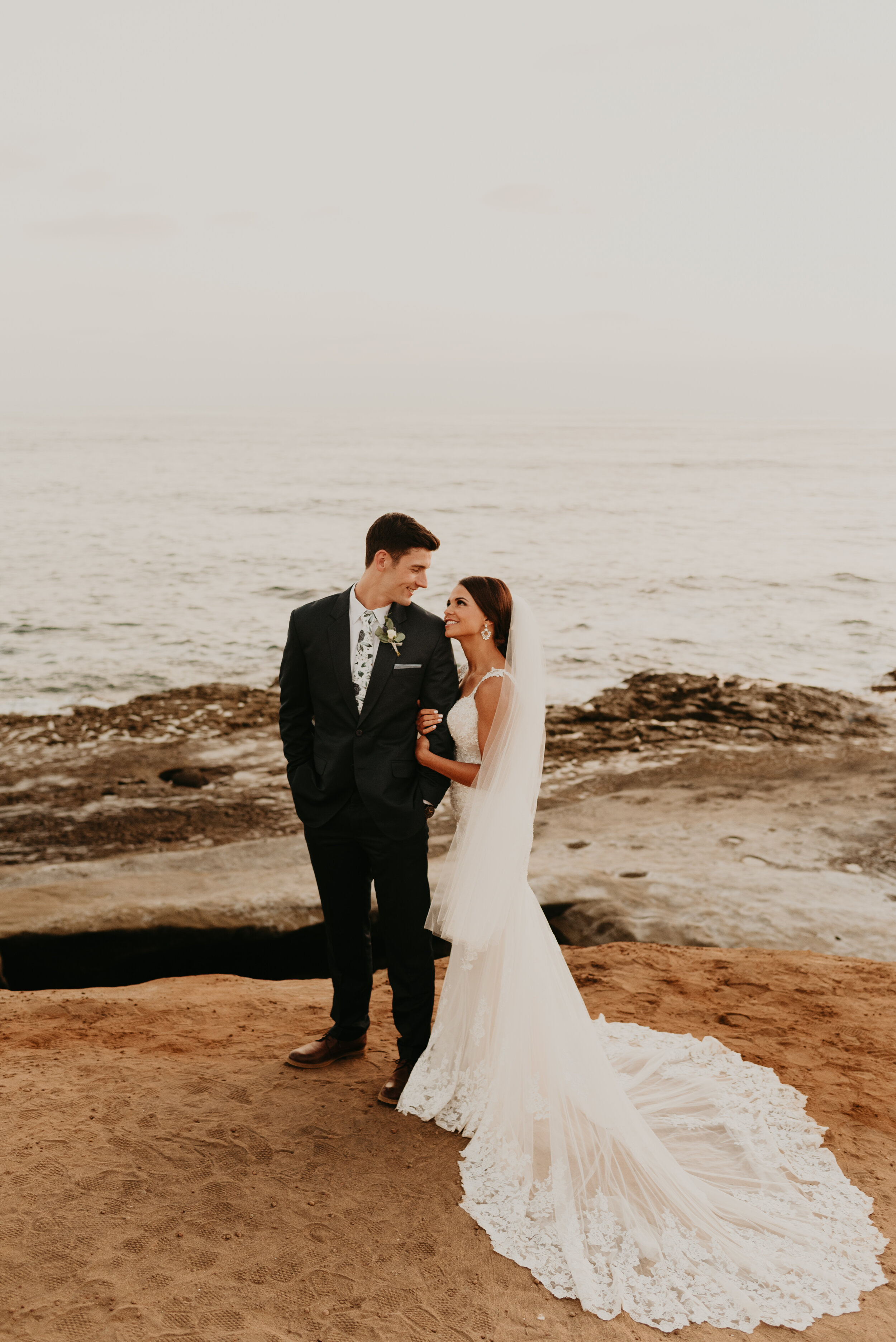 bride and groom in wedding outfits hugging at Sunset cliffs in san diego