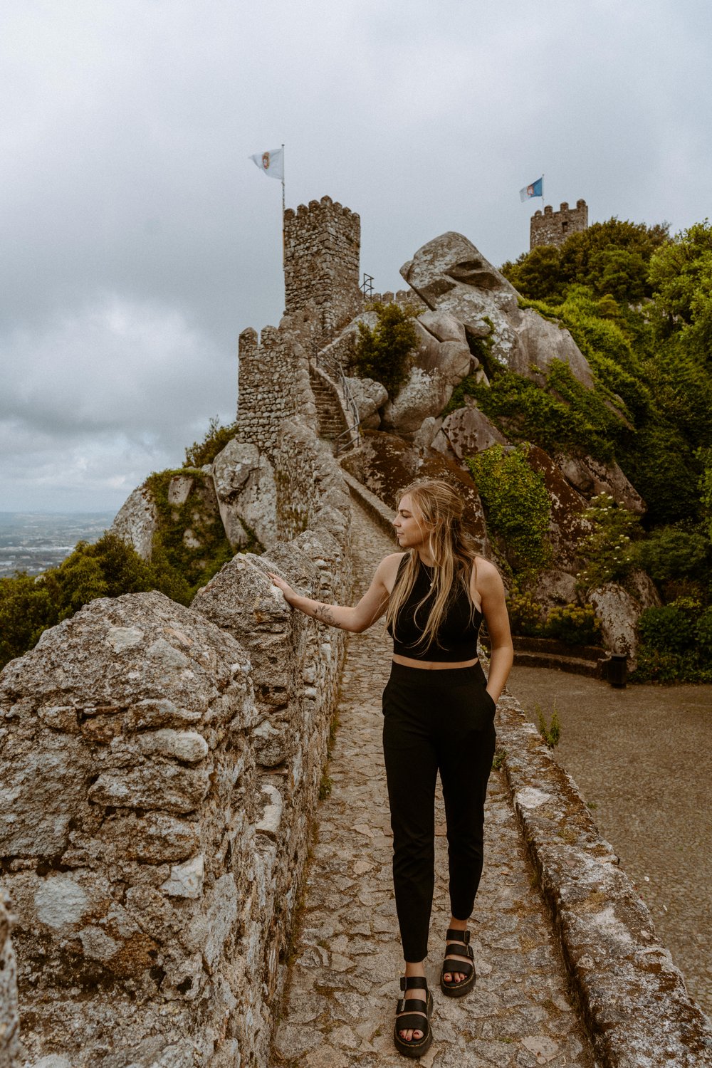 girl in black outfit standing on castle wall in sintra portugal