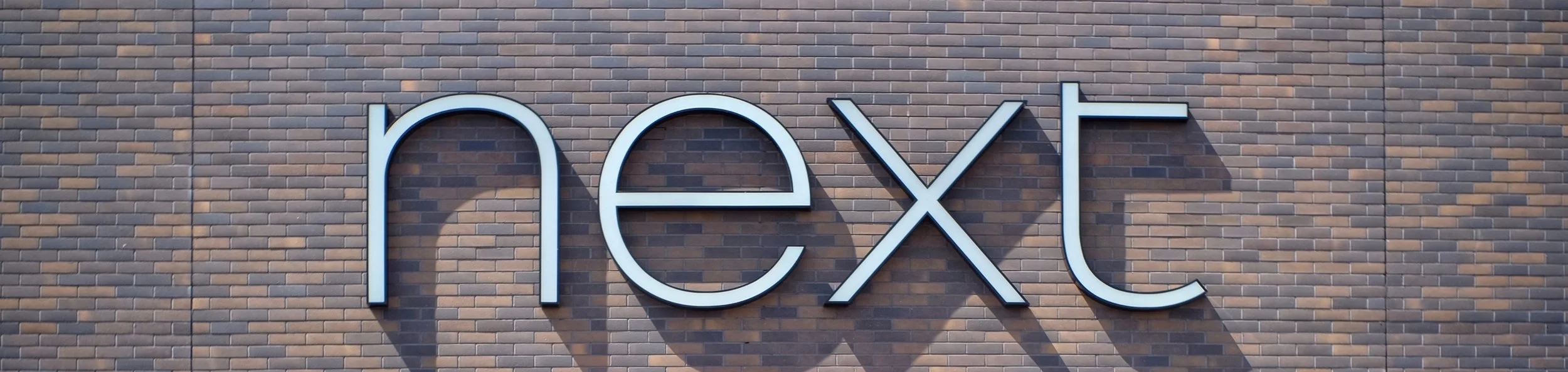 the picture has the word “next” over a brick wall THis picture is a cropped version of Photo by Viktor Forgacs on Unsplash