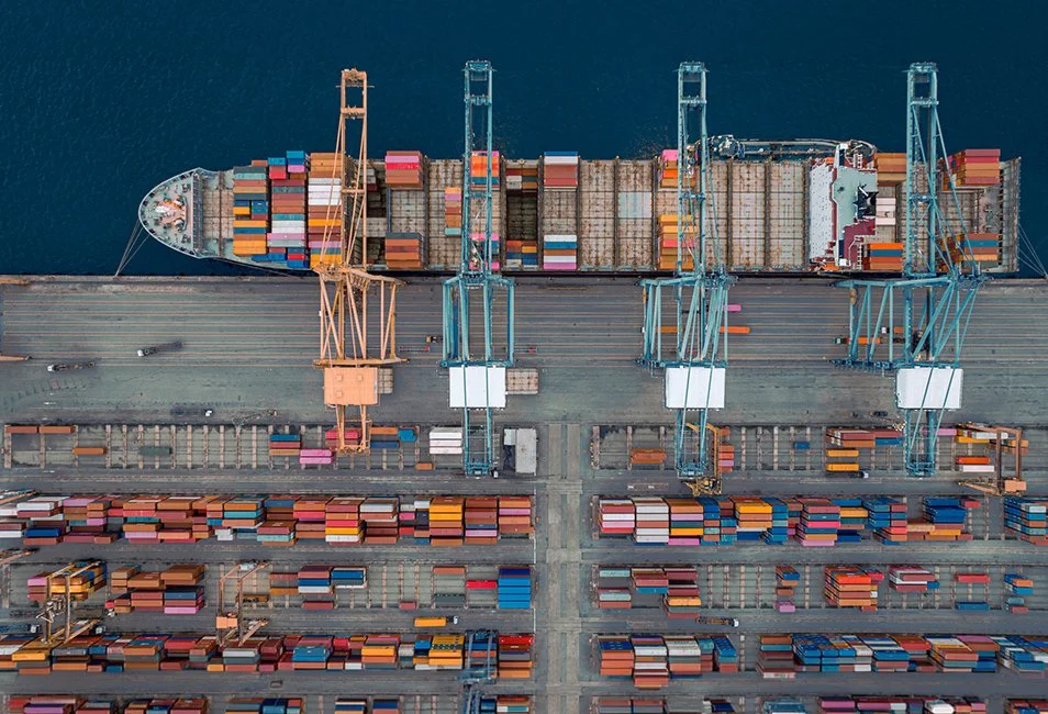 A bird's eye view of cargo containers being loaded on a ship