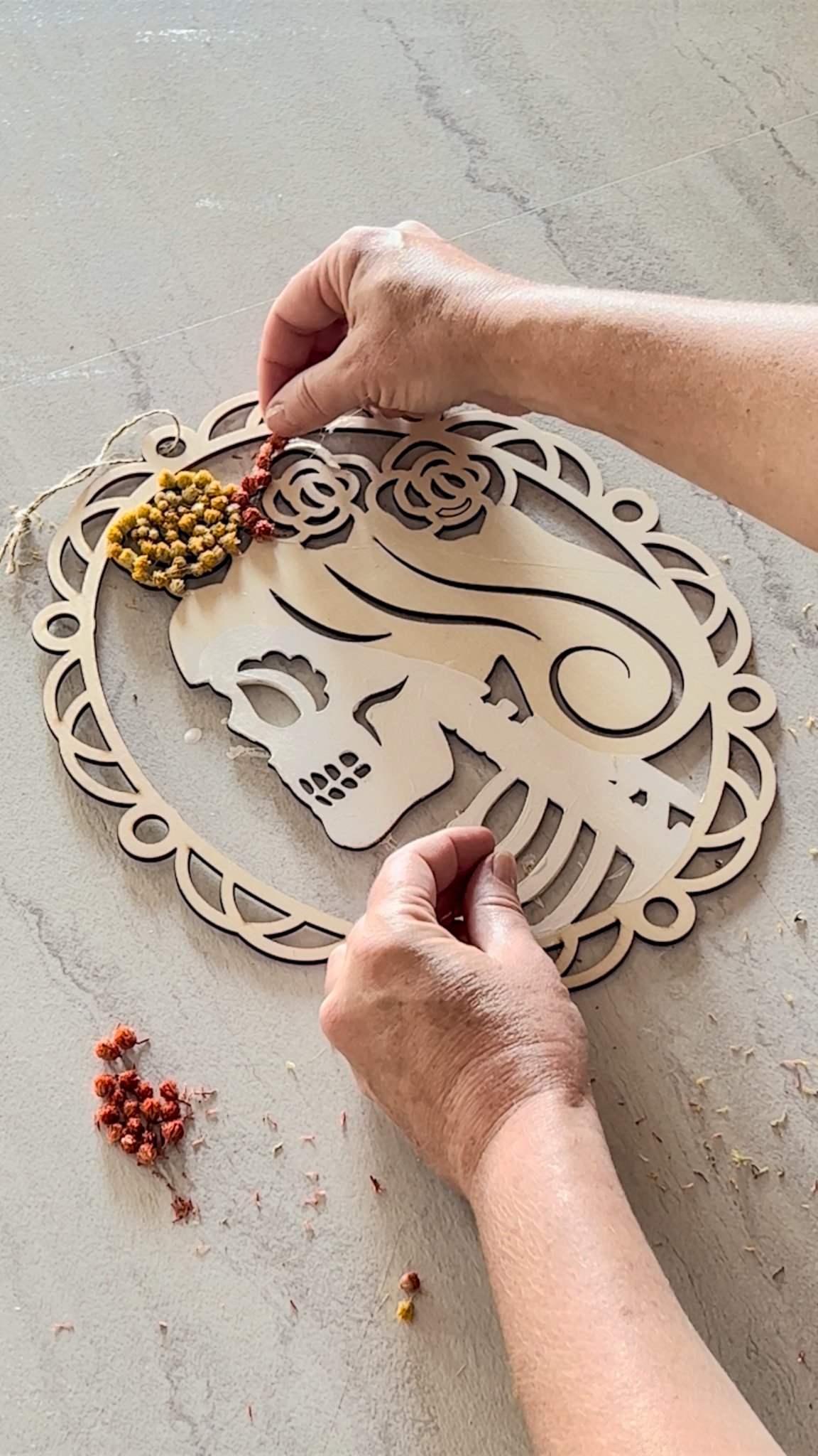 placing dried naturals onto calavera silhouette for dia de los muertos wreath