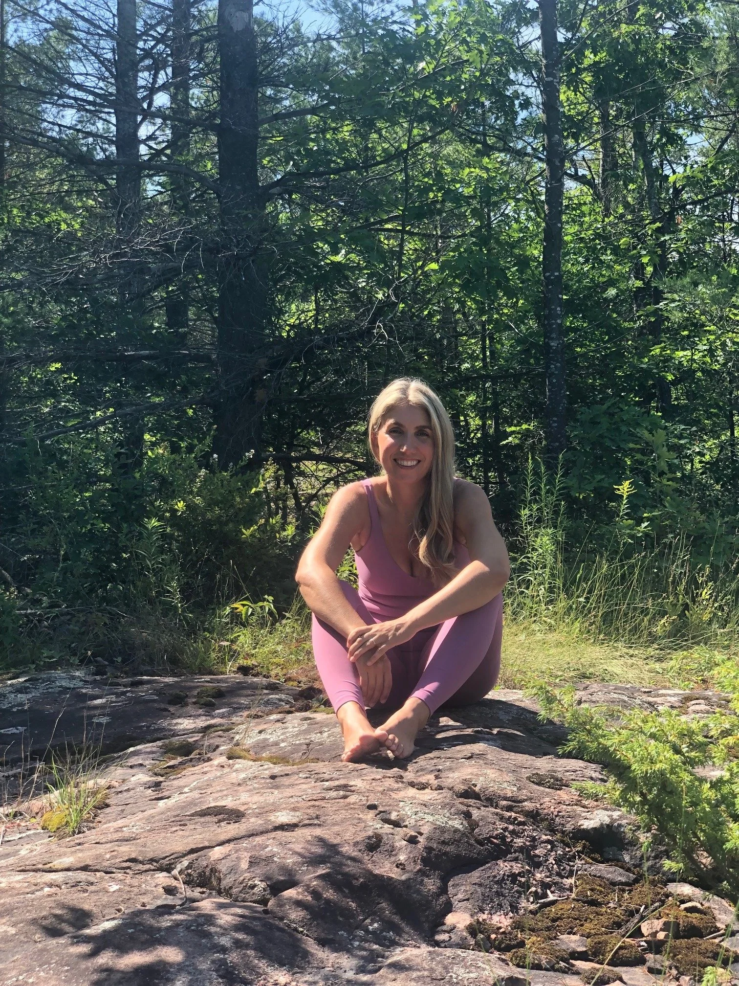 Allison McDonald Ace smiling and looking at the camera while seated on a rock outdoors