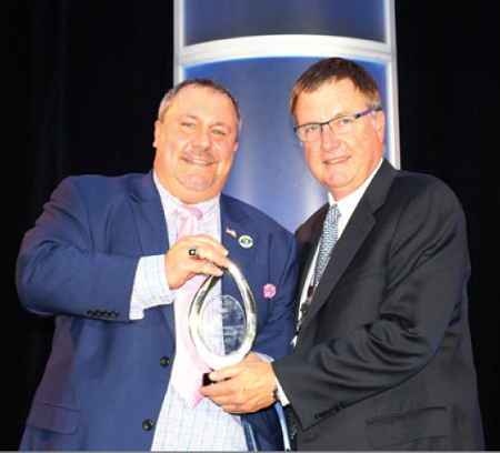 NAAA President Chad Bailey (left) awards Jeff Barber, owner of State Line Auto Auction, with the NAAA 2019 Pioneer Award