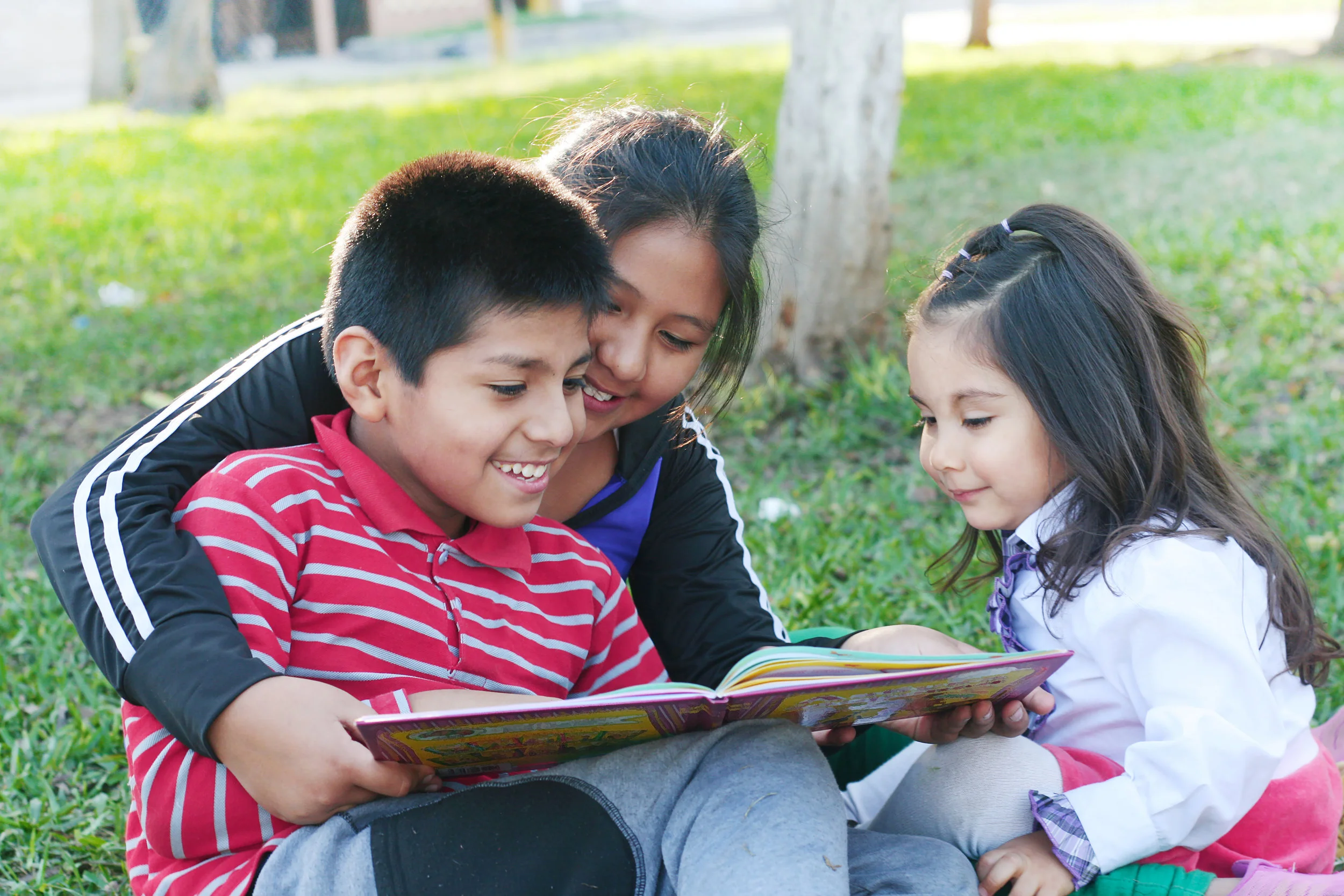 hispanic homeschool kids with book in park.jpg