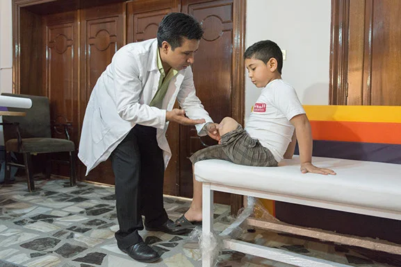 Eric Alvarez, Certified Prosthetic & Orthotic provider (CPO) evaluates Quasem, a Syrian refugees, for a new prosthetic leg. photo: Stephen Petegorsky