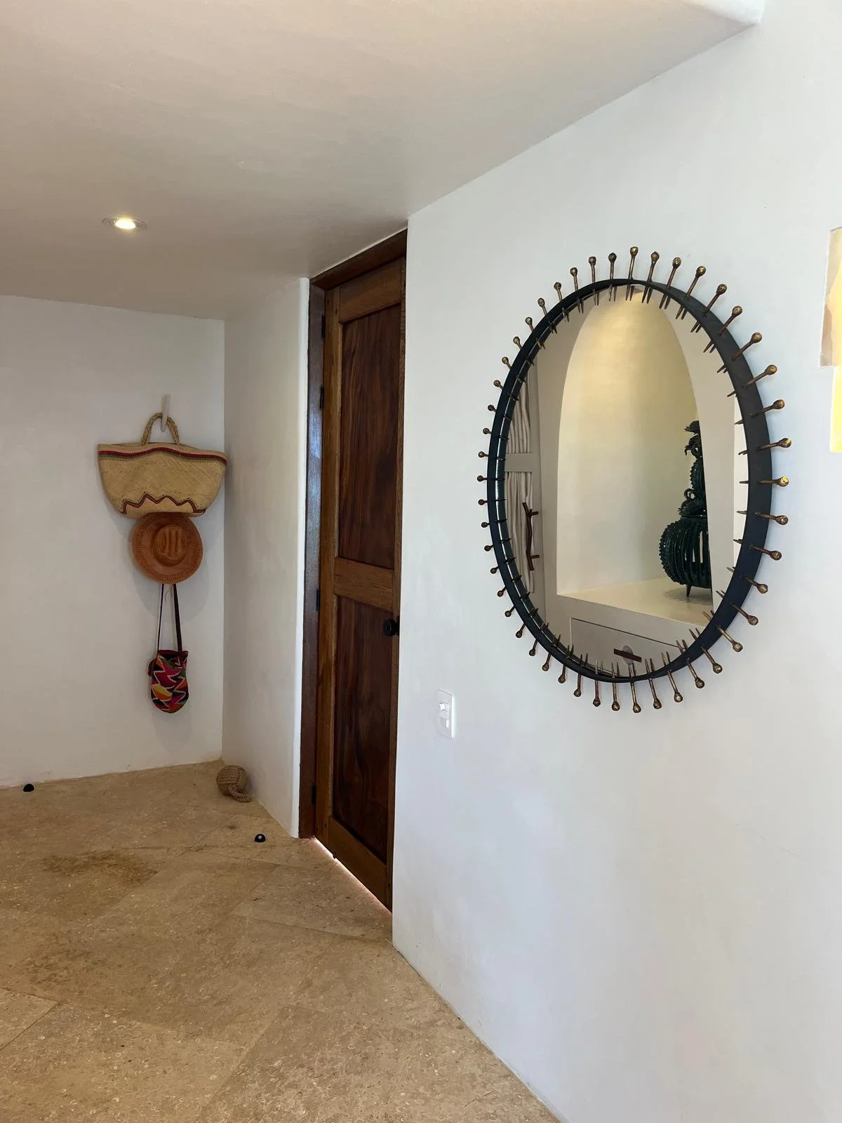 Sun suite entry with an iron sunburst mirror and woven hats, Casa Papelillo, interiors by Amathea