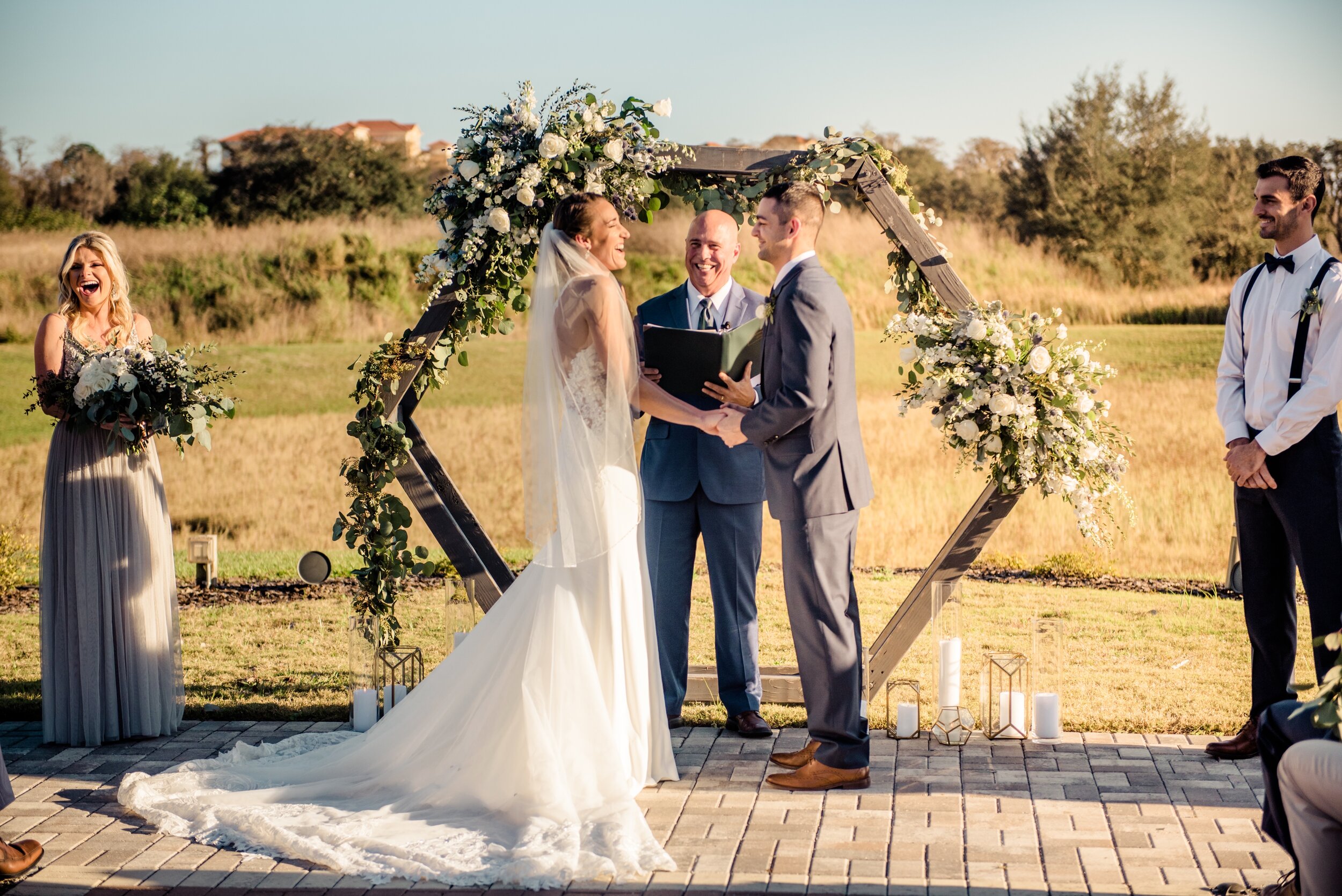 The bride and groom in front of the hexagon wooden arch at Formosa with white and green floral and geometric vases