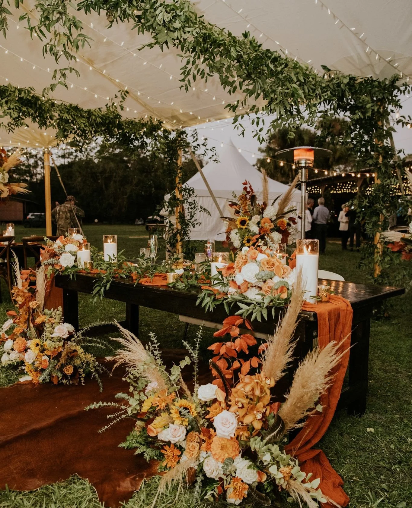 fall tent reception goals!🍂🌿 Fall foliage + greenery vines = gorgeous contrast!⁠
⁠
Our couple held their wedding festivities on their private ranch - so the cowhide rug accents were the perfect rustic touch! Double tap and comment to show your love