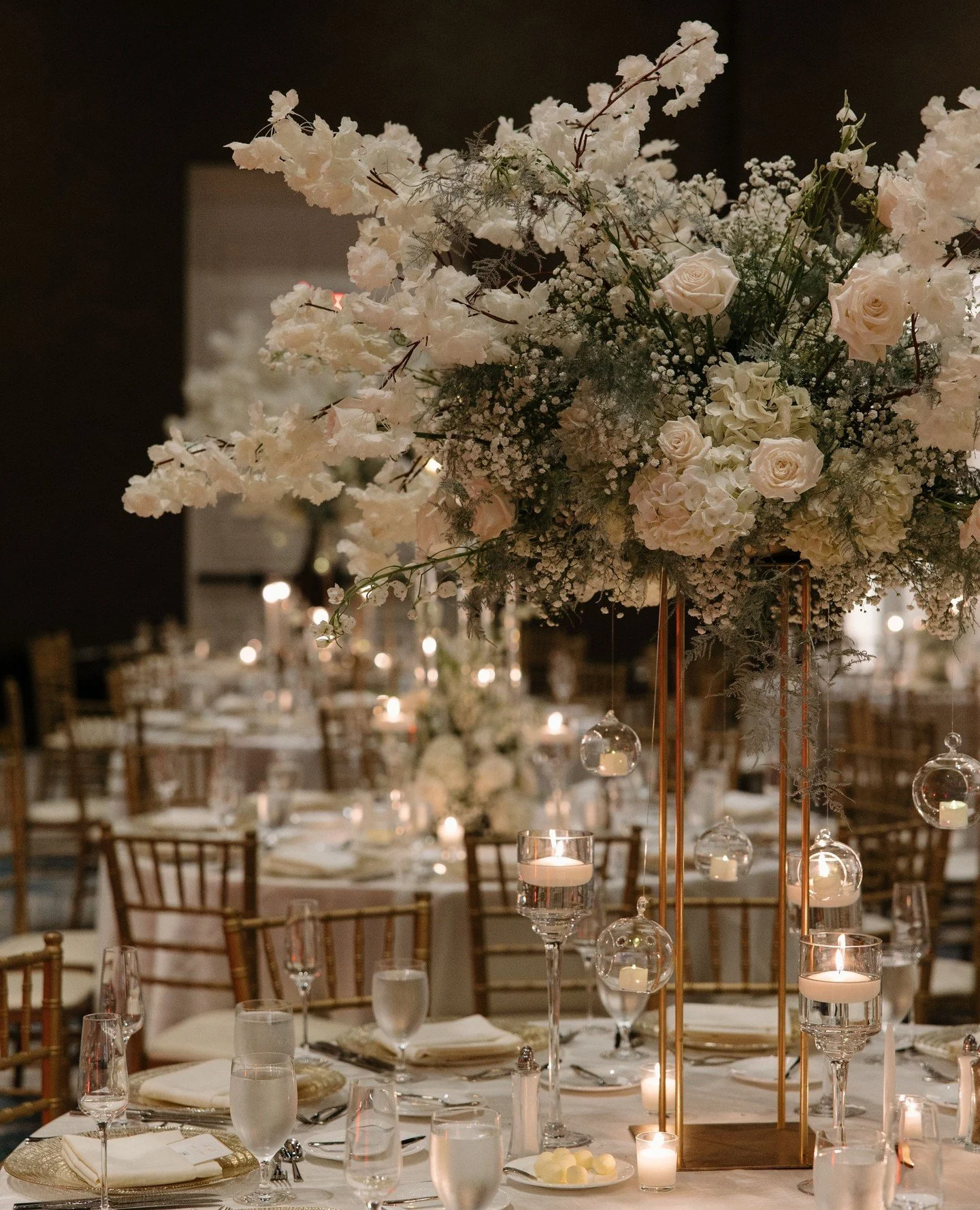 the dreamiest reception✨️ Swipe to see this stunning ballroom!⁠
⁠
Airy elevated centerpieces, silk blossom trees, modern crystal candelabras, and lush long elevated floral bridges filled this ballroom with so much beauty! Double tap and comment to sh