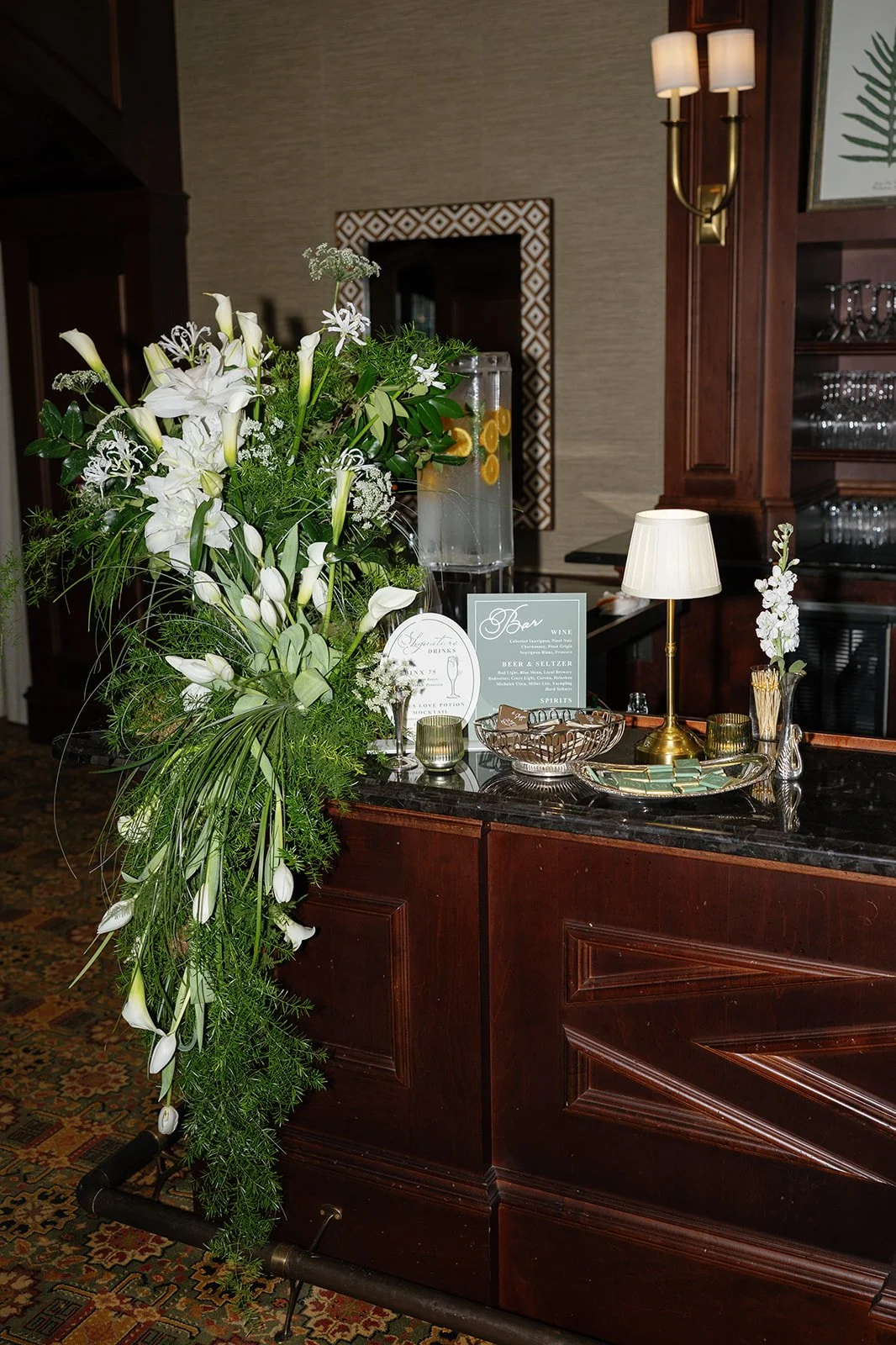 Airy white floral arrangement decorating the bar at a Crane Club wedding, featuring tulips, calla lilies, and delicate greenery, designed by Bluegrass Chic.