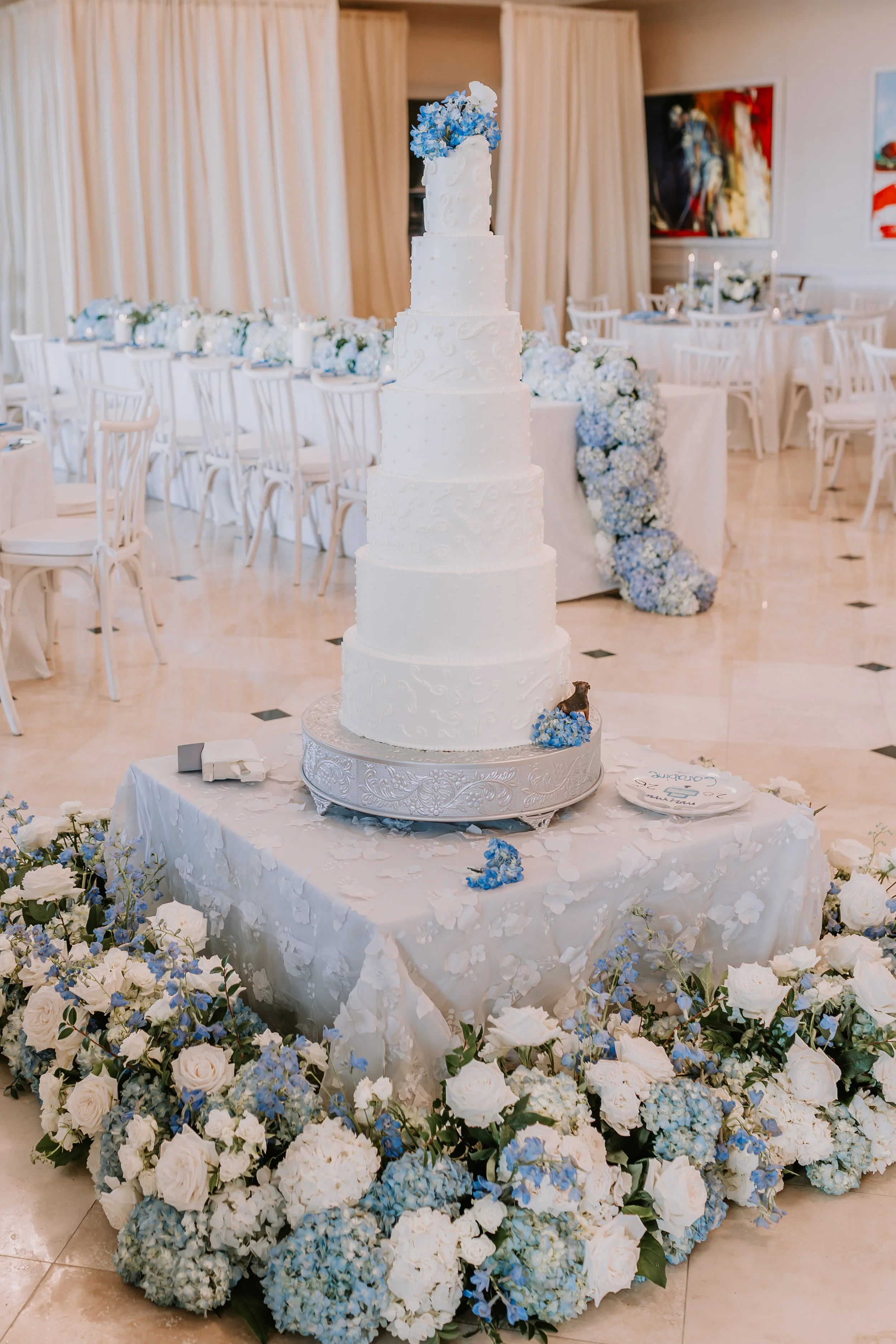 Lush blue and white floral arrangements surrounding wedding cake table, designed by Bluegrass Chic.