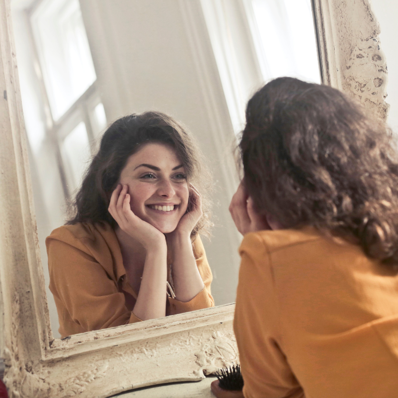 a woman looking in the mirror as representation of self image