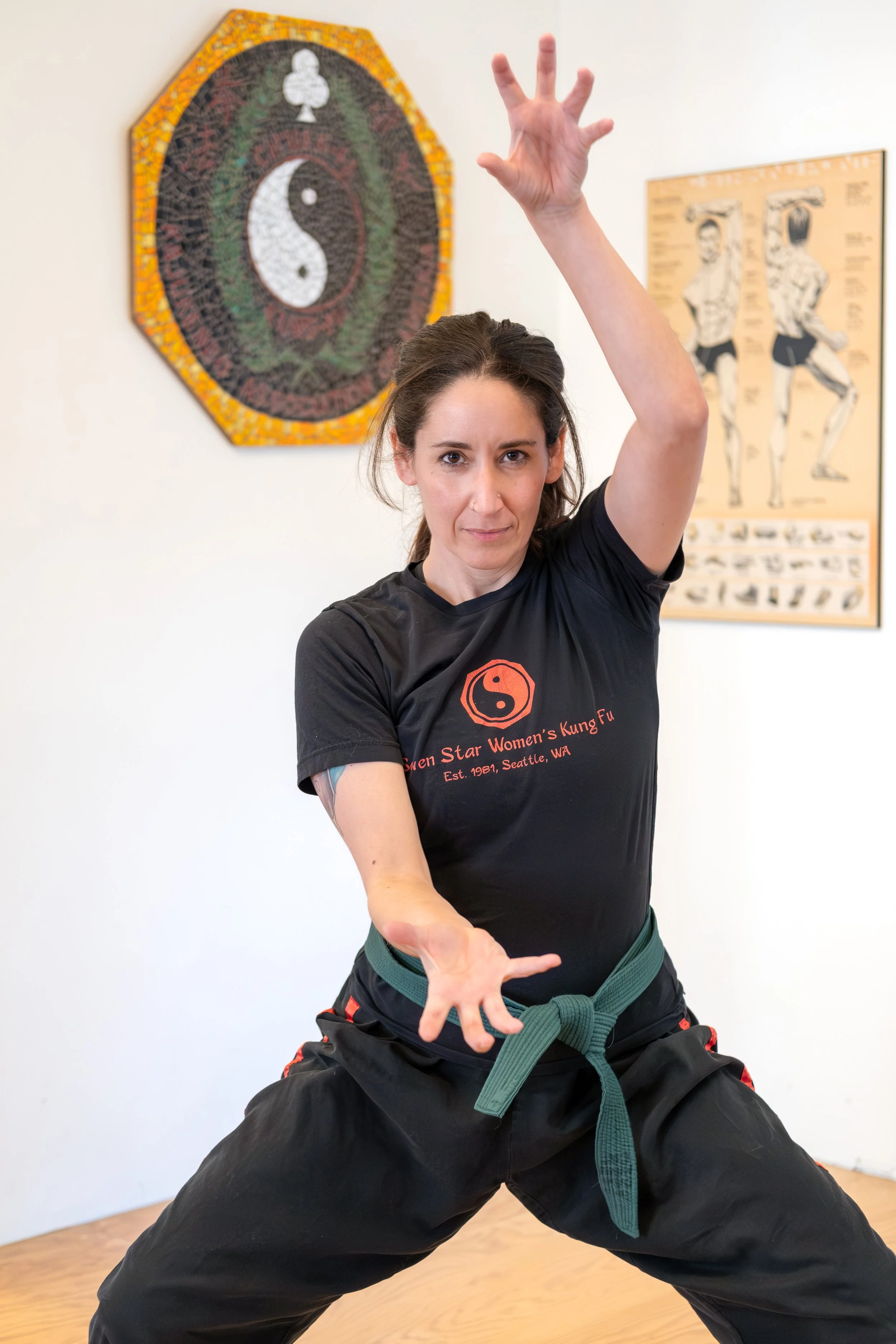 A brown-haired woman in a pony tail is looking at the camera in a kung fu post