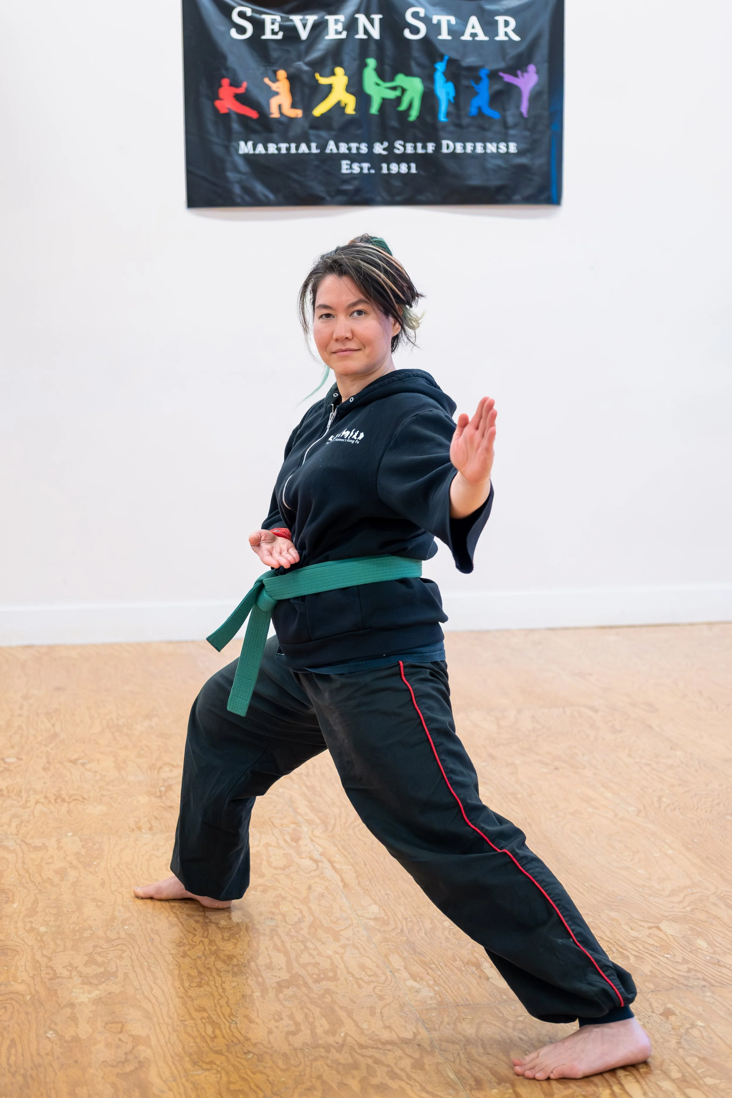 A dark-haired woman looks directly at the camera in a kung fu pose