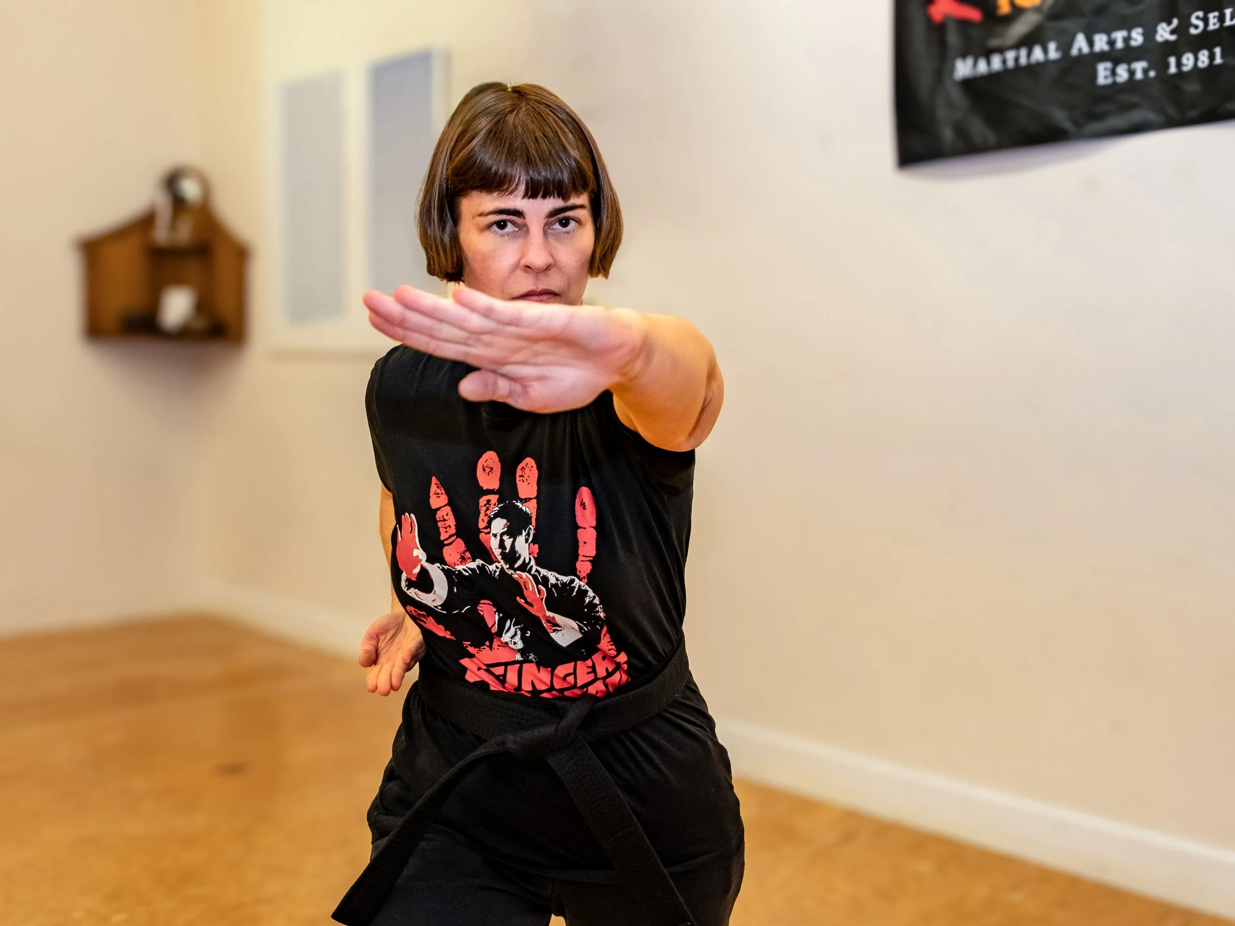 A woman with brown hair looking at the camera in a kung fu pose