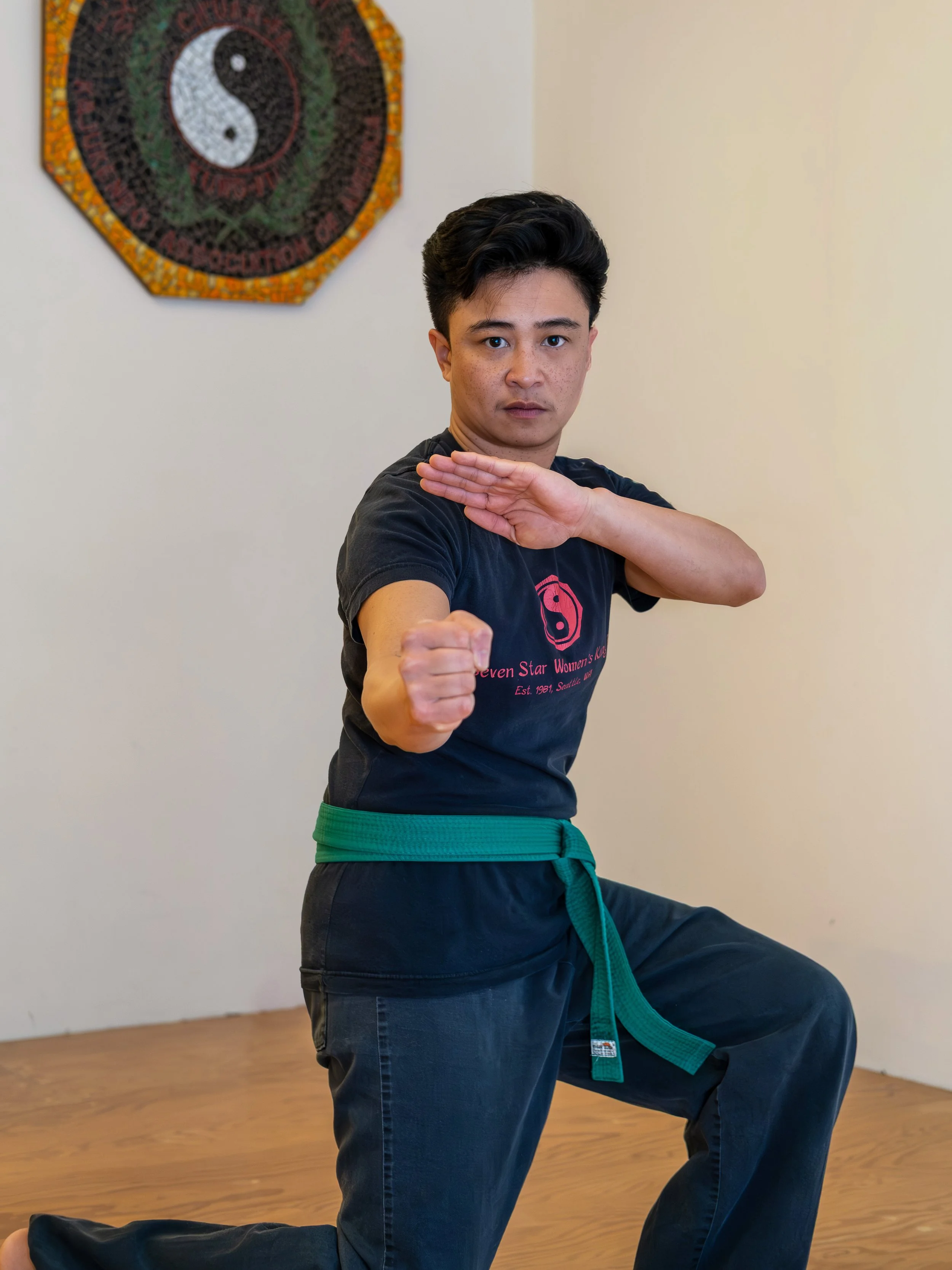 A person with dark short hair looking at the camera doing a kung fu stance
