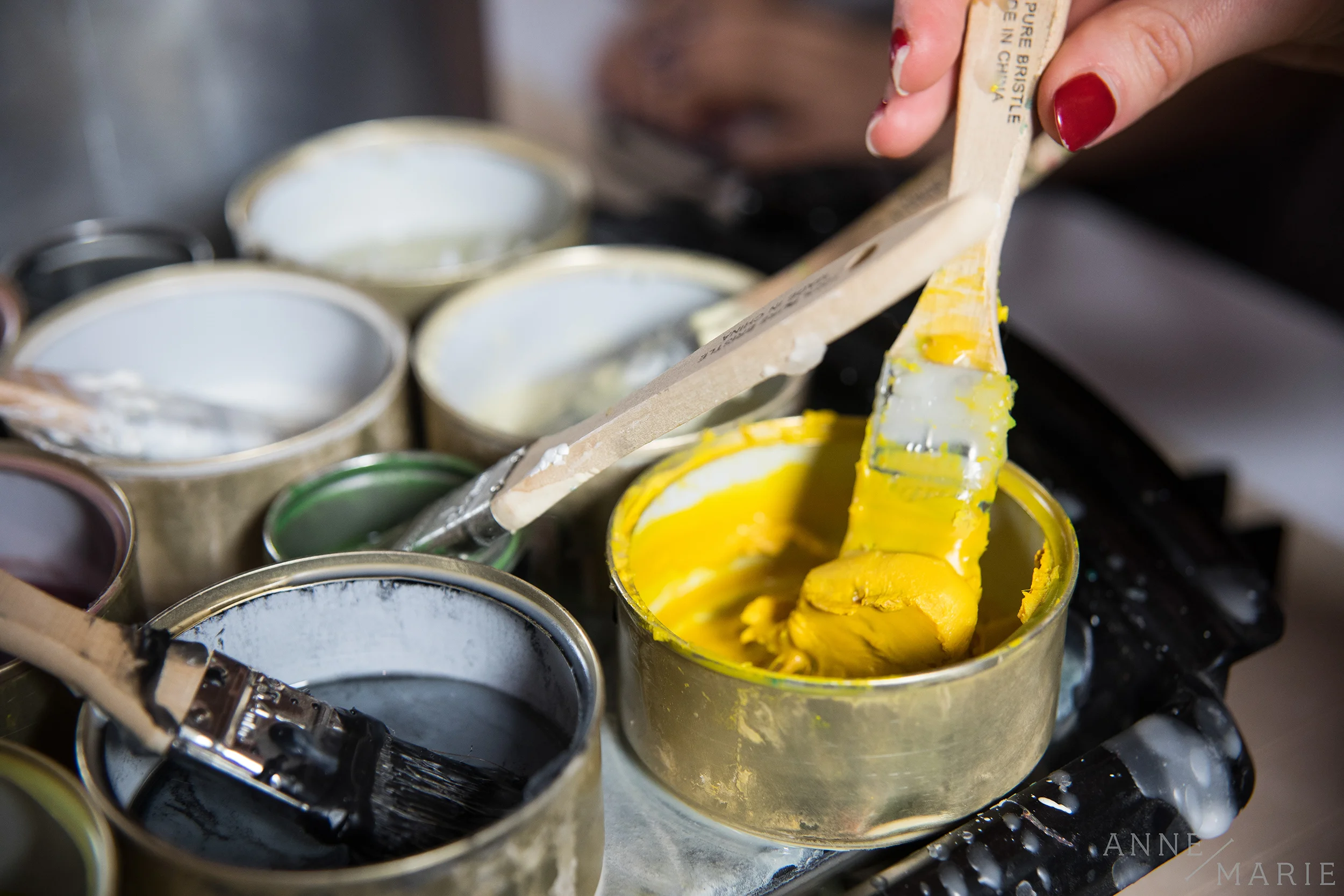 Amber's brushes sit in repurposed cat food tins on top of a griddle. As the griddle warms, the wax melts.