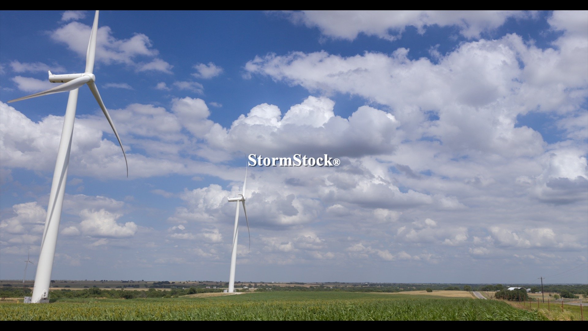Wind turbines spin on wind farm as cumulus clouds drift by, rural Oklahoma