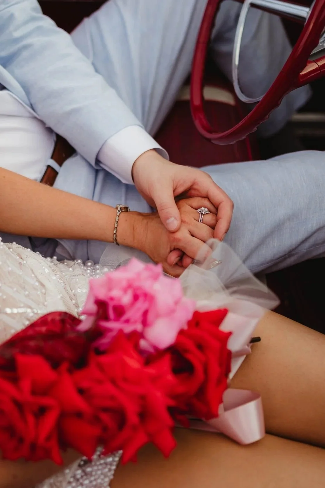 a close up image of a las vegas bride and groom holding hands, showing off her rings and flowers