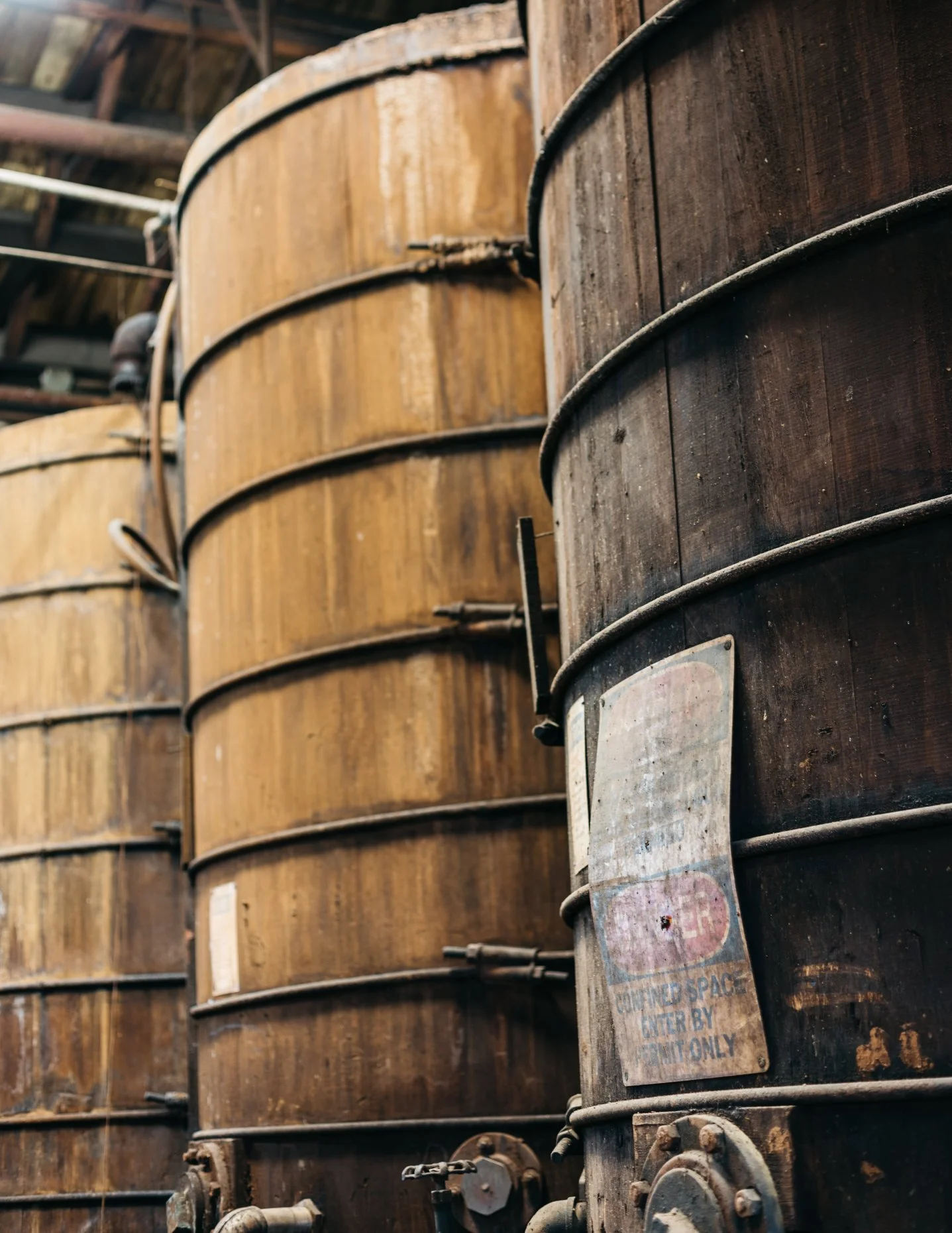 Row of large, tanning tanks in a leather tannery with a weathered label on one tank