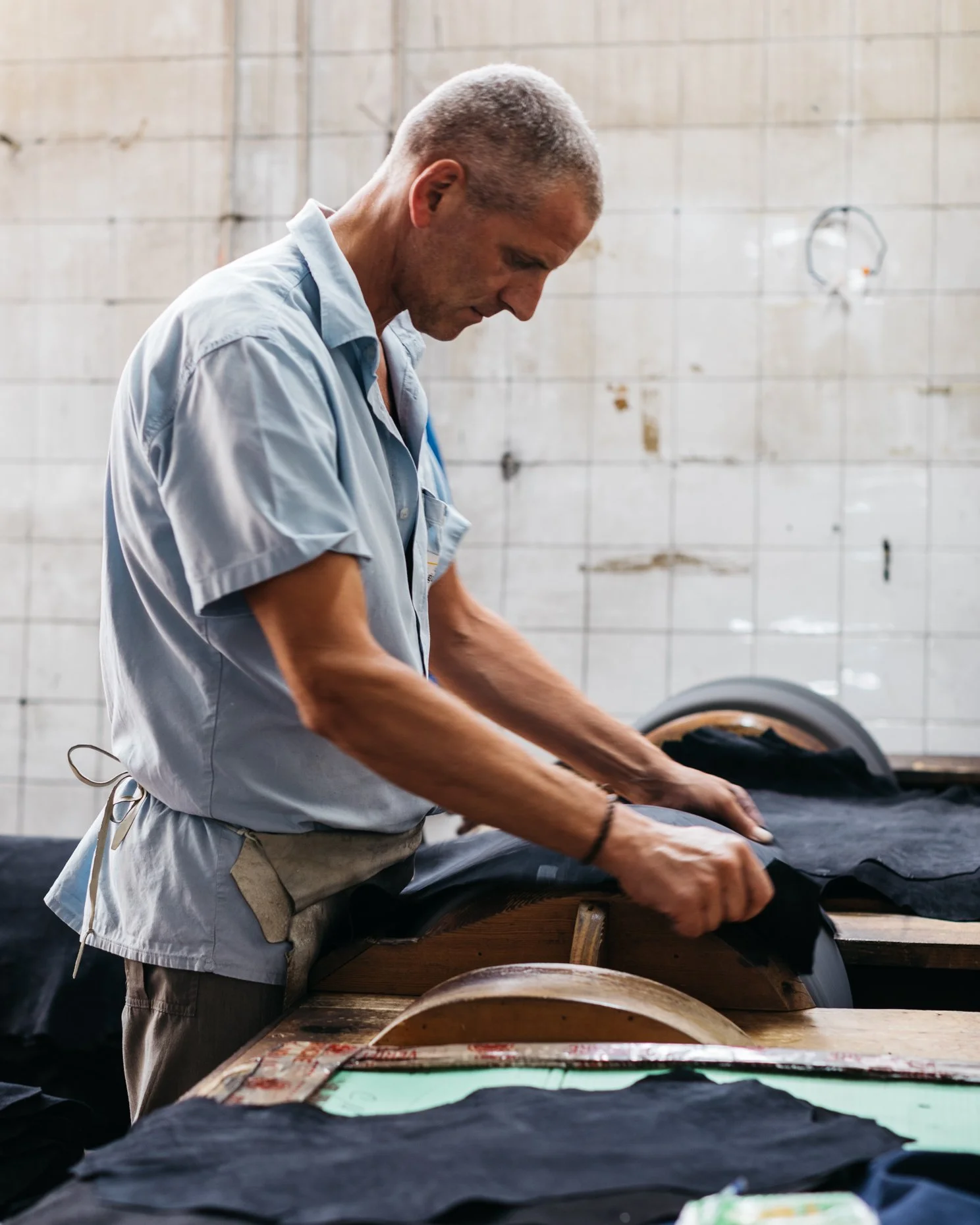 A man working in a tannery, buffing leather on a machine.
