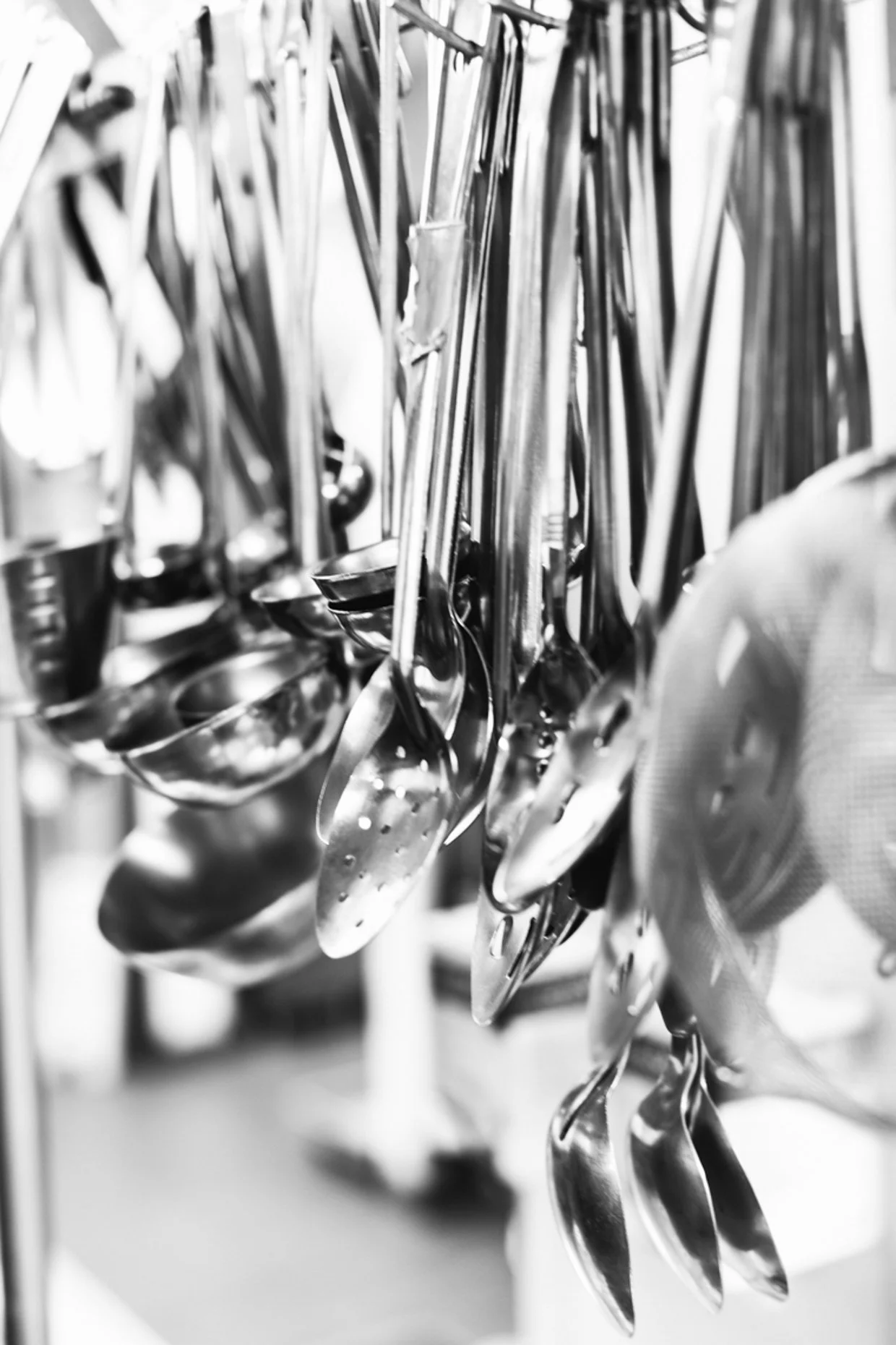A row of hanging stainless steel kitchen ladles and utensils.