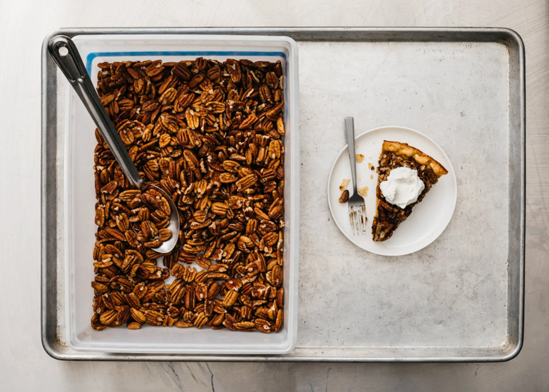 A tray of pecan pieces with a slice of pecan pie topped with whipped cream on a separate plate.