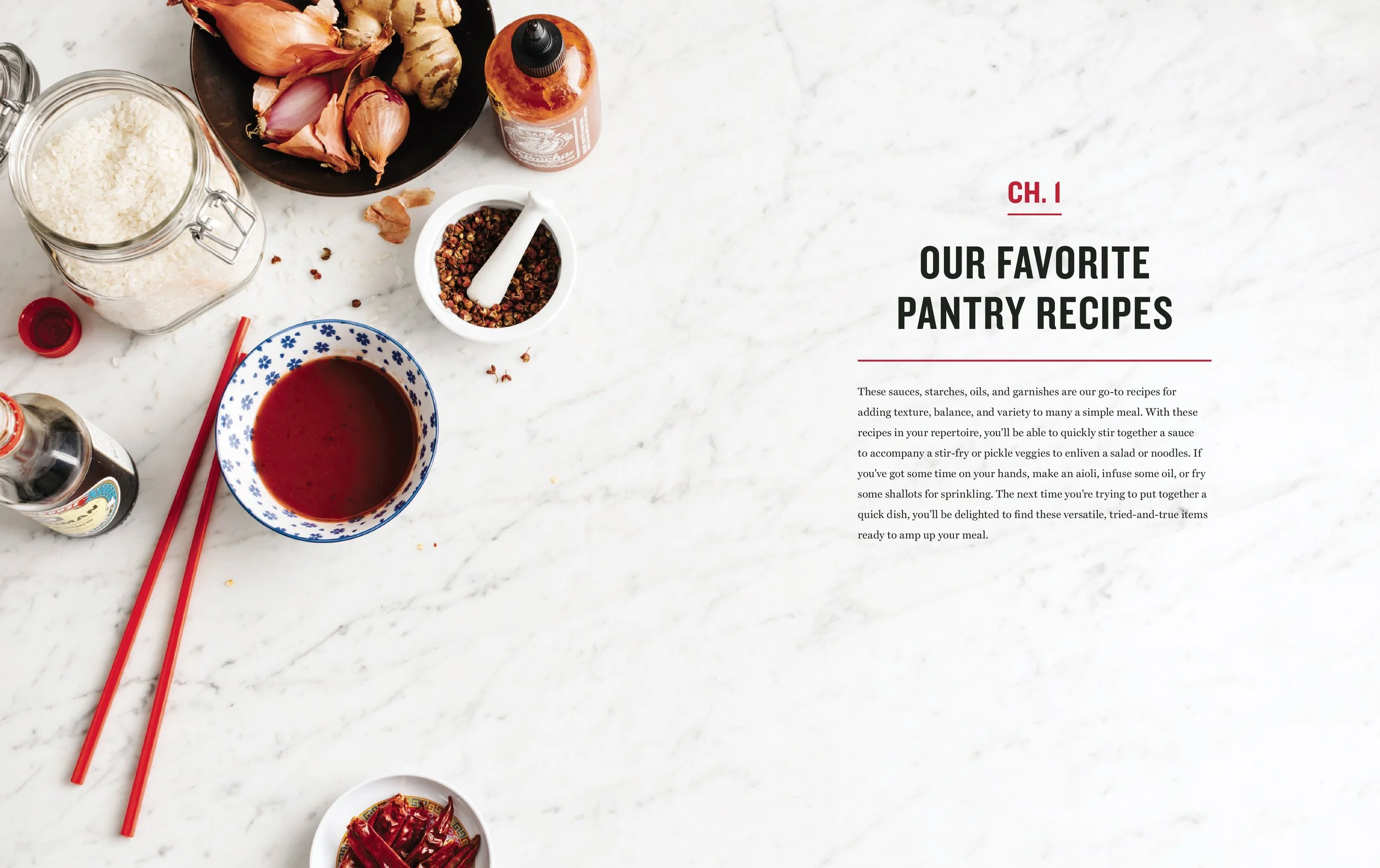 A kitchen countertop with ingredients for Asian cuisine, including garlic, ginger, rice, soy sauce, dried chili peppers, and a bowl of red sauce, along with red chopsticks, and a sheet of paper titled 'Our Favorite Pantry Recipes'.