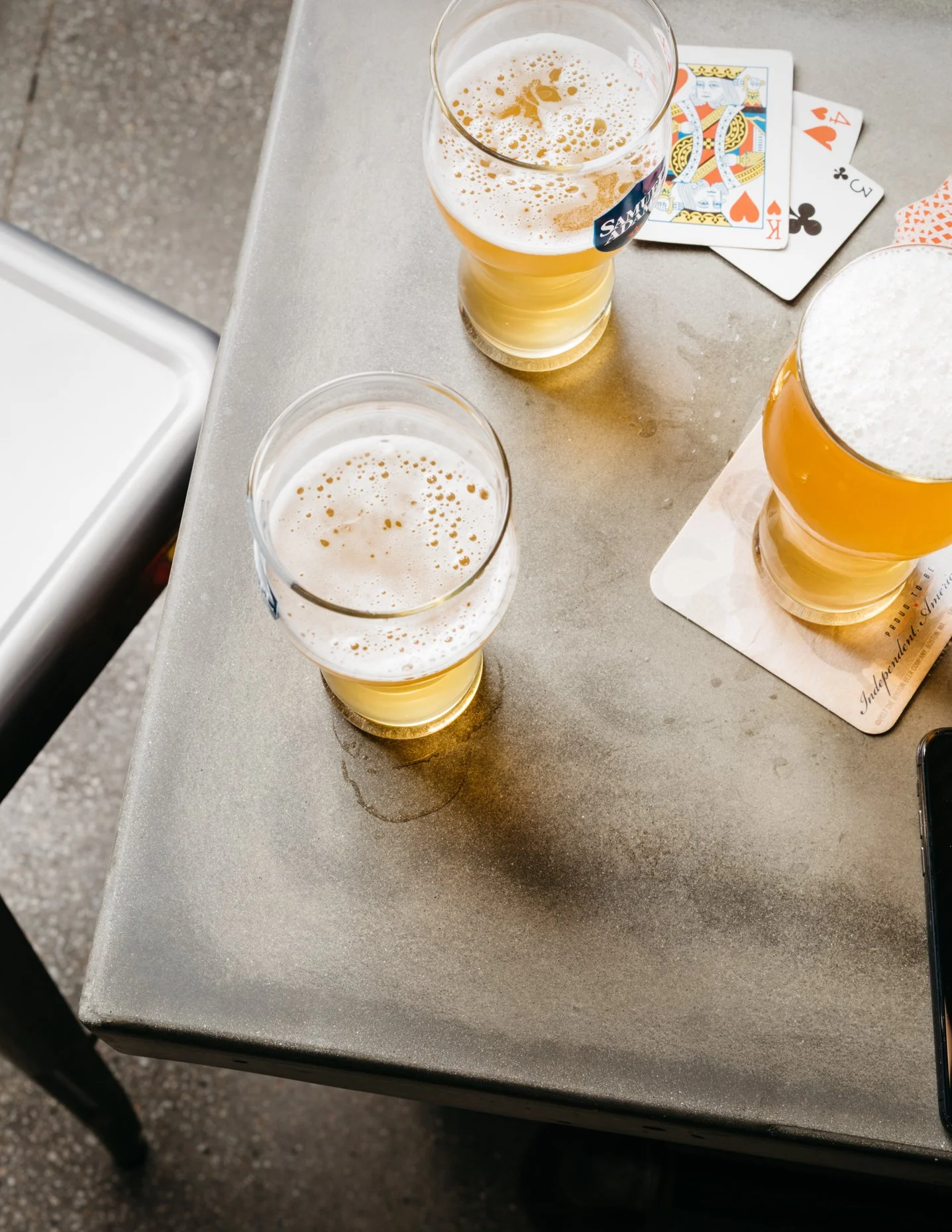 Two glasses of beer and a deck of playing cards on a table.