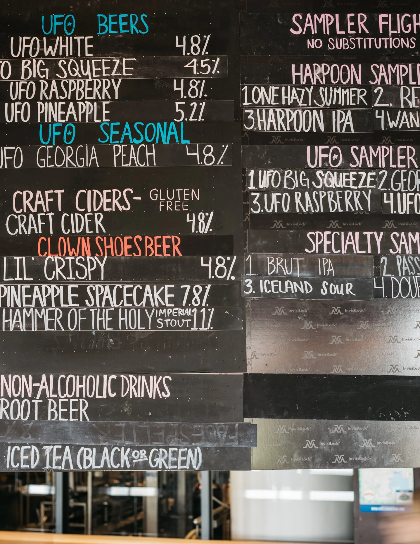 A chalkboard menu with sections titled UFO Beers, Sampler Flight, UFO Seasonal, Craft Ciders, Clown Shoes Beer, and Non-Alcoholic Drinks, listing various beers, ciders, and drinks with their percentages and descriptions.