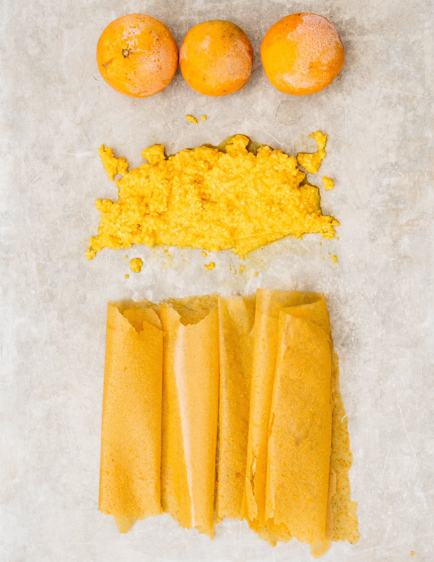 Frozen Oranges, orange pulp, and dried orange parchment arranged on a light-colored surface.