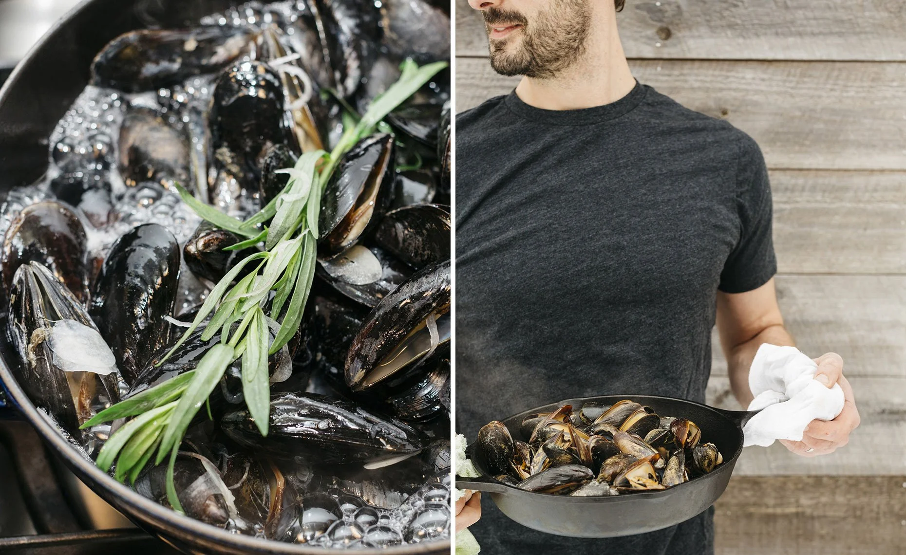 A man holding a black pan of cooked mussels with a sprig of greens and a cloth in his hand, standing in front of a wooden wall.