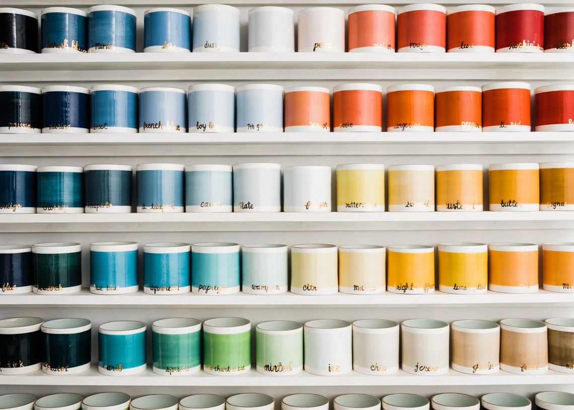 Glaze test-jars arranged on white shelves, each labeled with different colors and names.